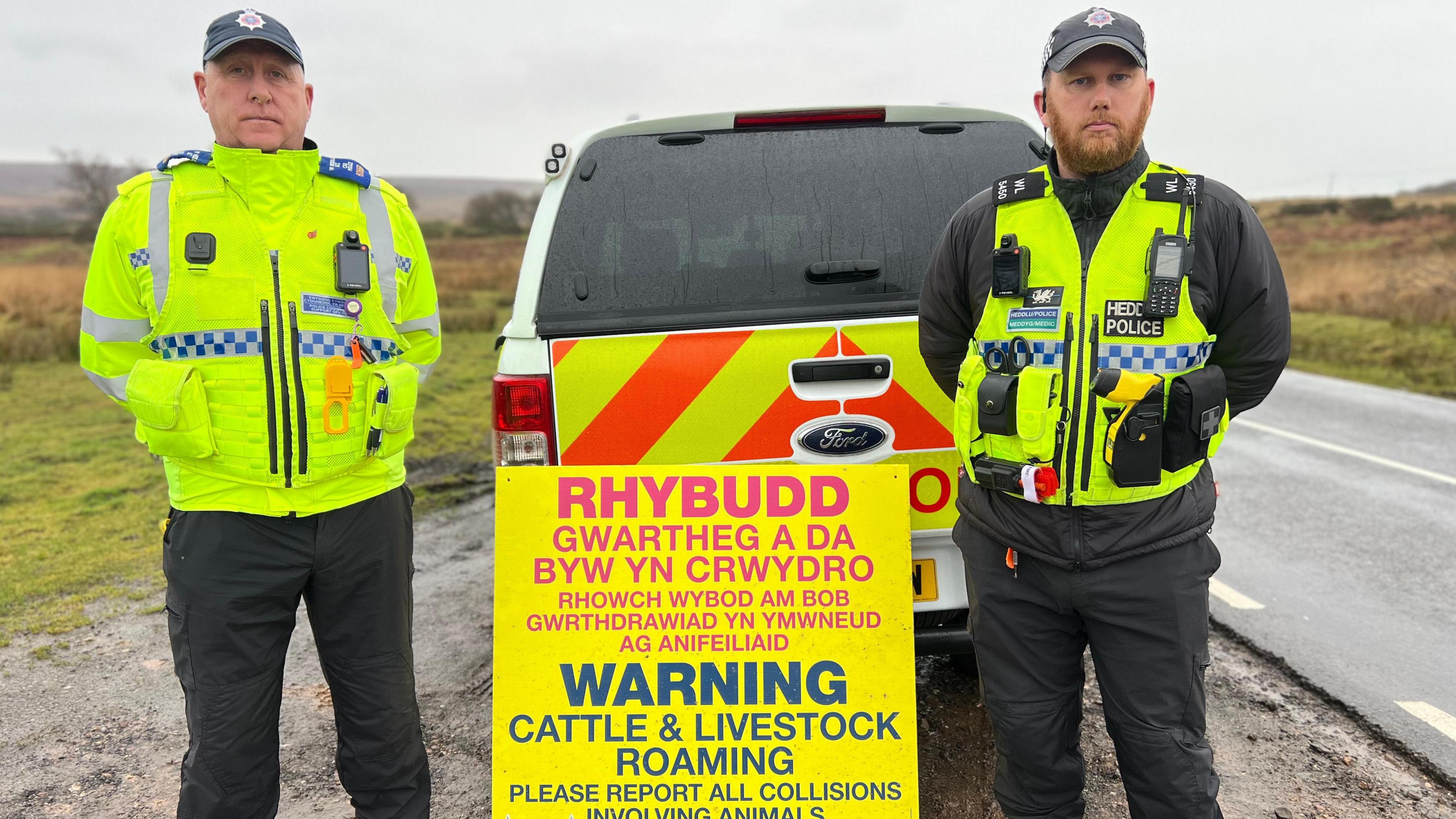 Police officers next to a warning sign