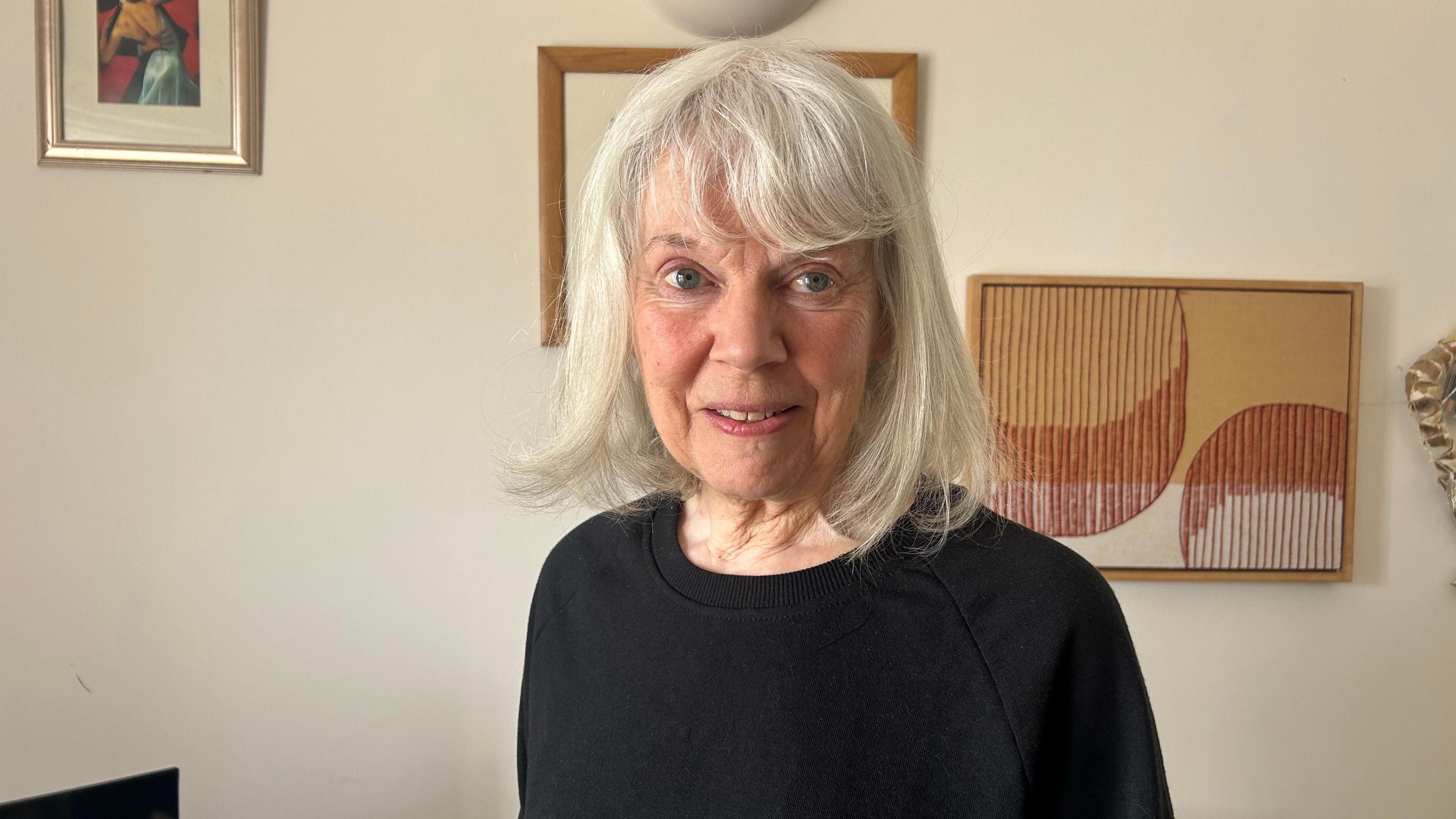 Roslyn Moore gyda gwallt gwyn a gwisgo siwmper ddu
