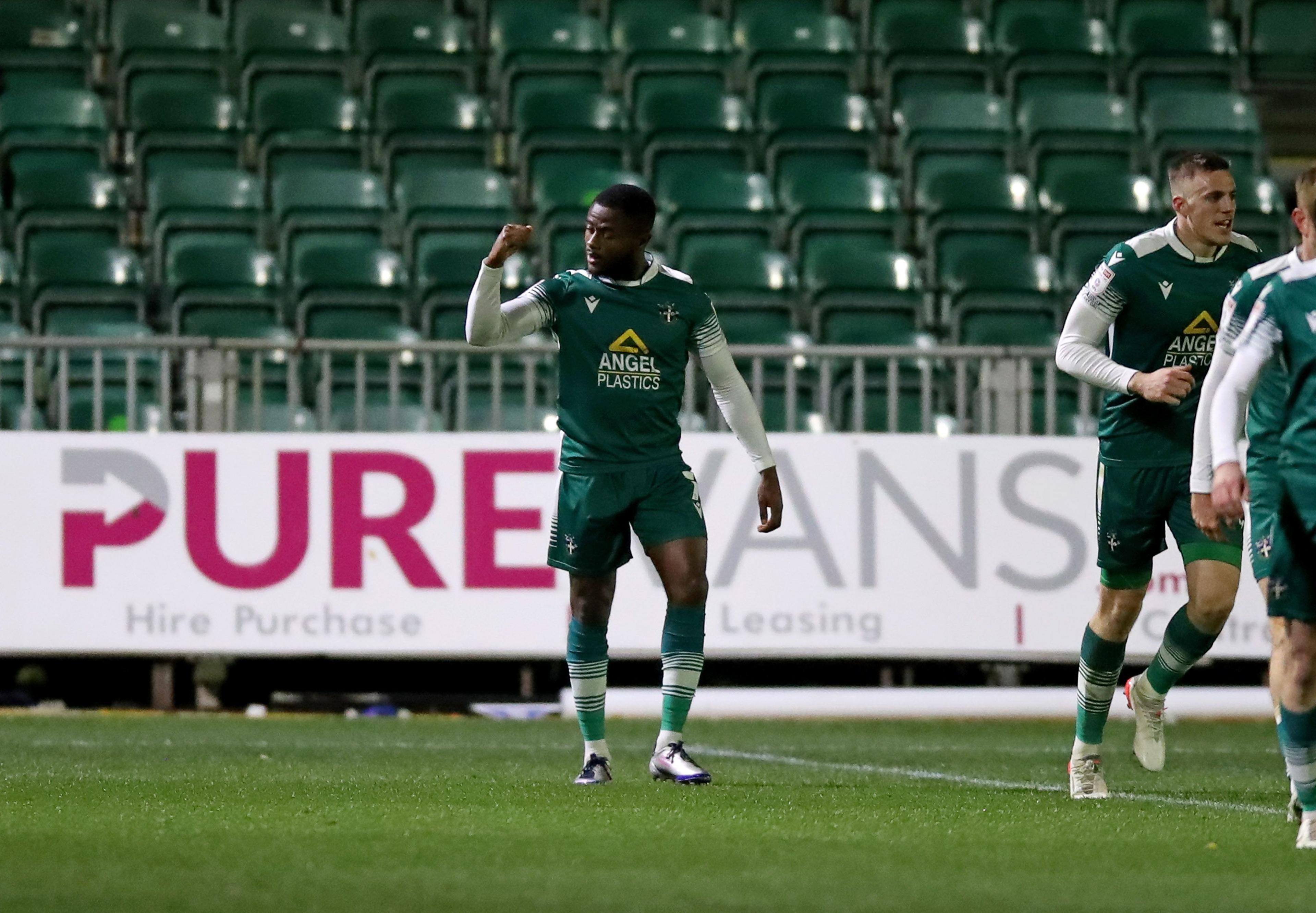 David Ajiboye celebrates while wearing a Sutton kit after scoring at Rodney Parade
