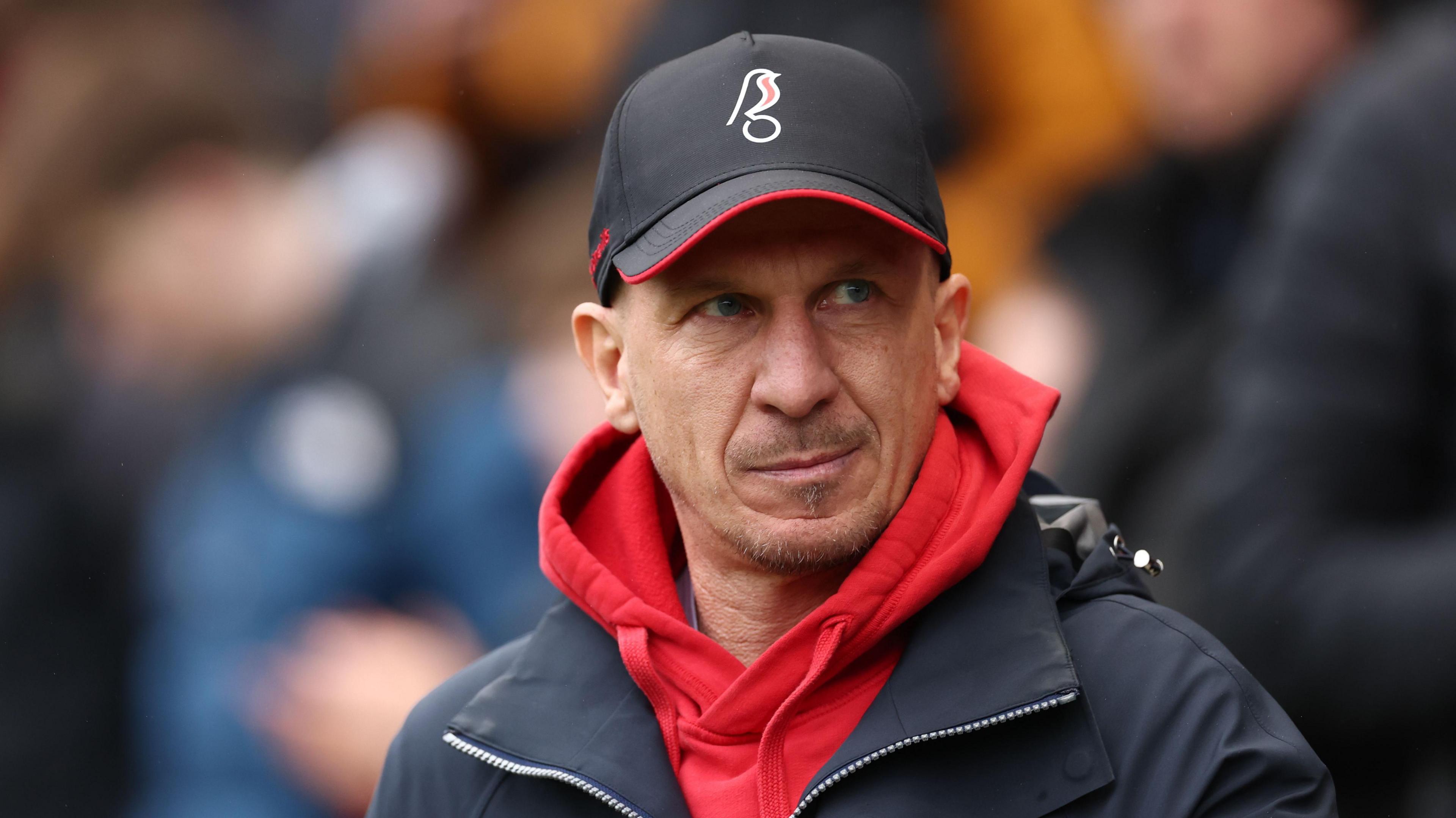 Gerhard Struber in the City technical area wearing a Robins cap