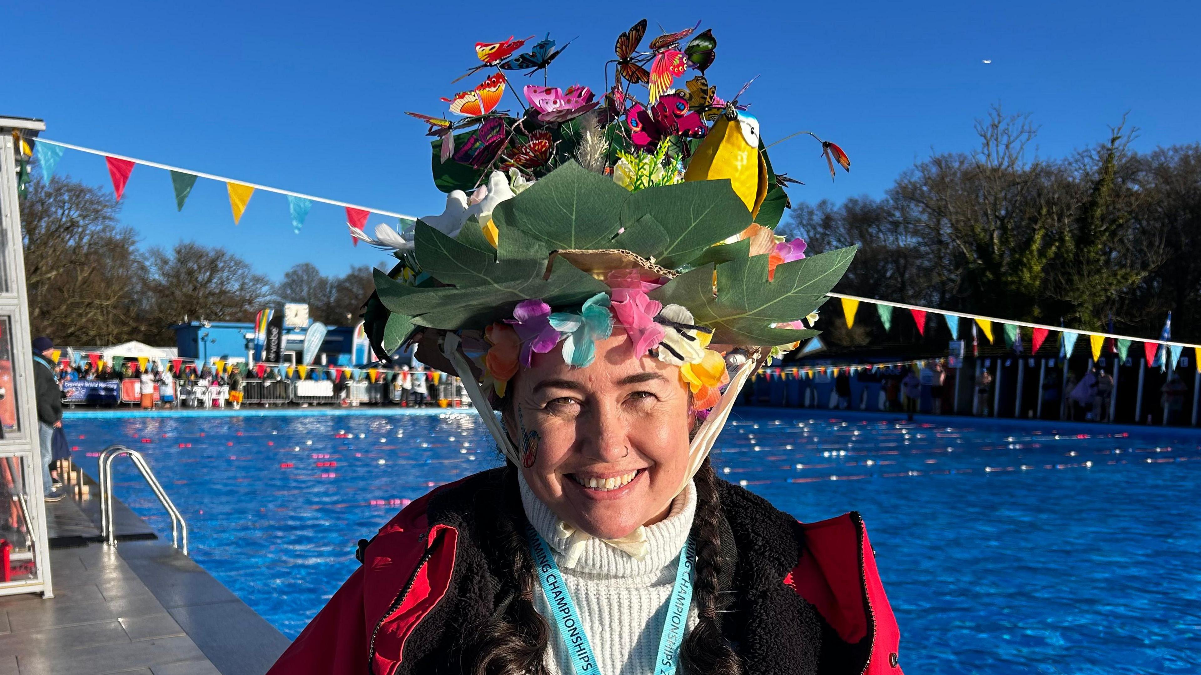 A woman wears an ornate hat decorated with plants and butterflies.