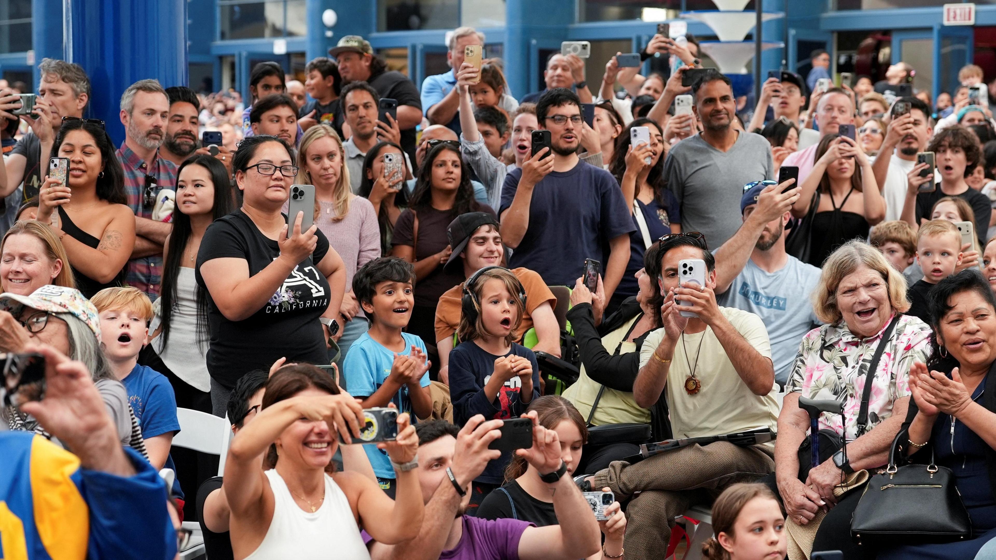 Crowds of people gawp and take photos at the Artemis viewing parties at the San Diego Air and Space Museum in San Diego.