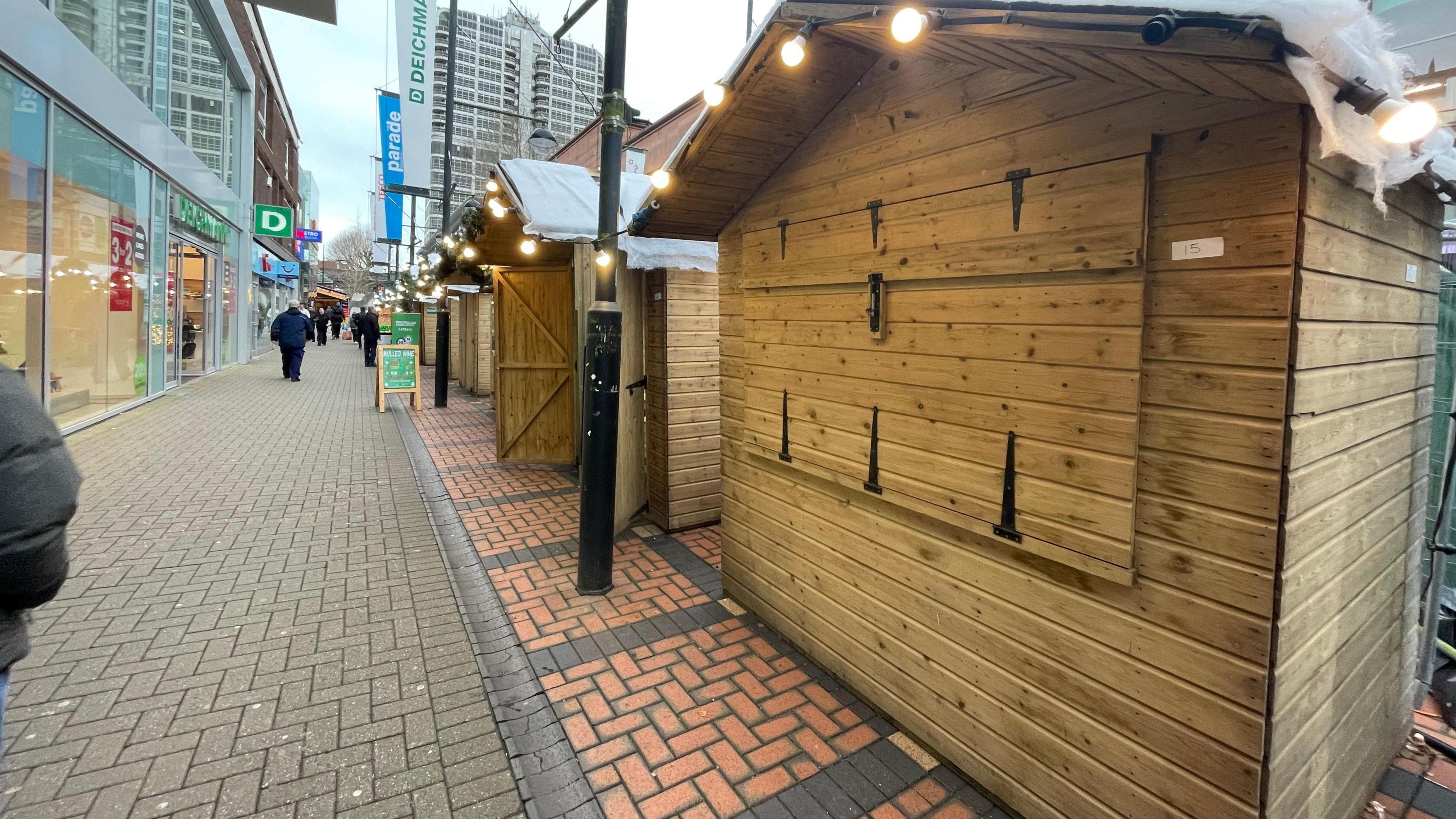 A row of stalls at the Swindon Christmas Market, one is clearly closes with only one further down the row having a sign out the front