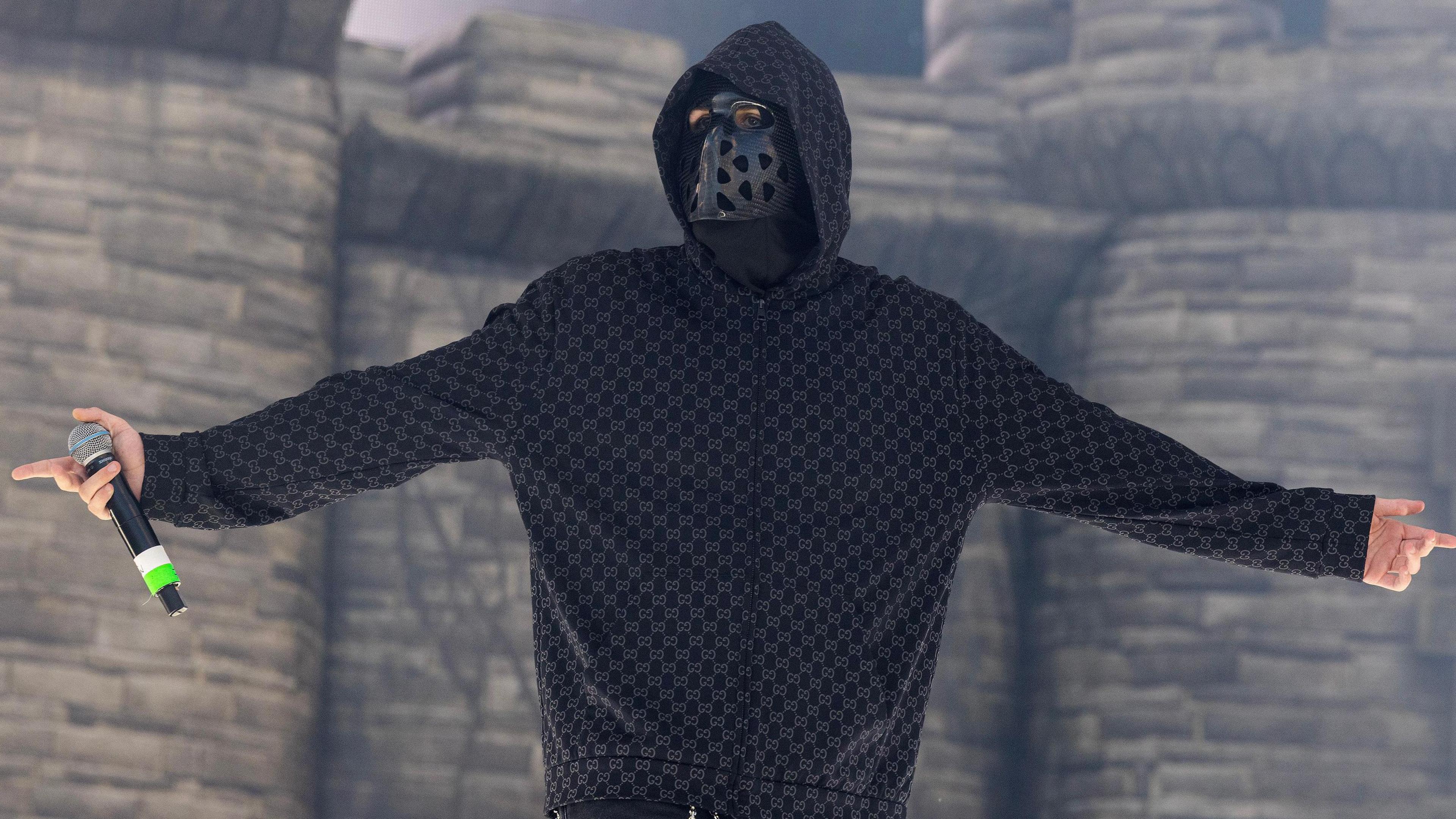 EsDeeKid performs successful  beforehand   of a blow-up castle during a acceptable   successful  Illinois.  He is seen looking astatine  the crowds portion    holding a microphone and wearing a achromatic  disguise  with holes and a hoodie.