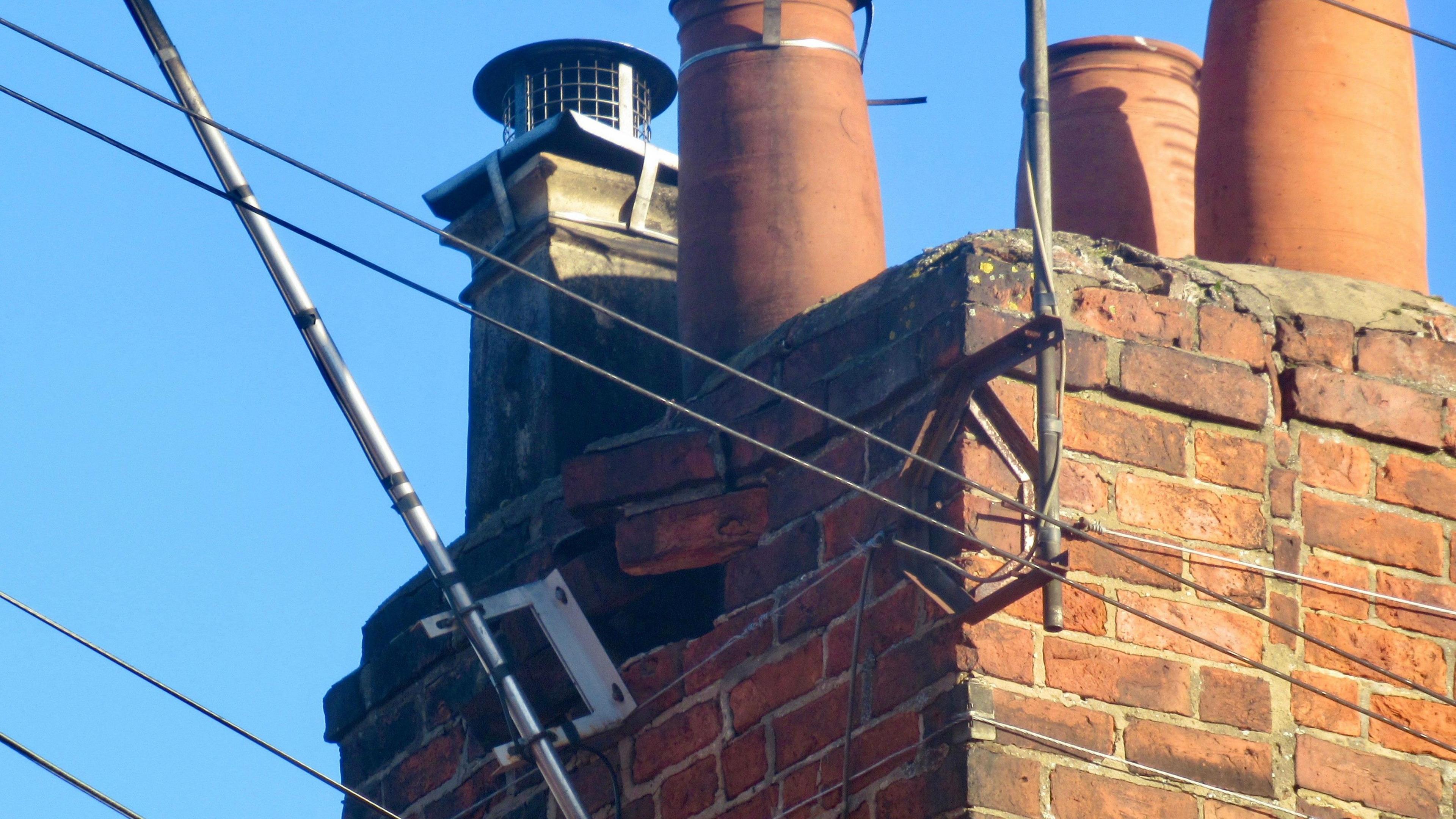 Bricks have been pulled out of a chimney and an aerial is coming away from the structure after damage caused by a storm. The picture has been taken after severe weather and shows a clear, blue sky.