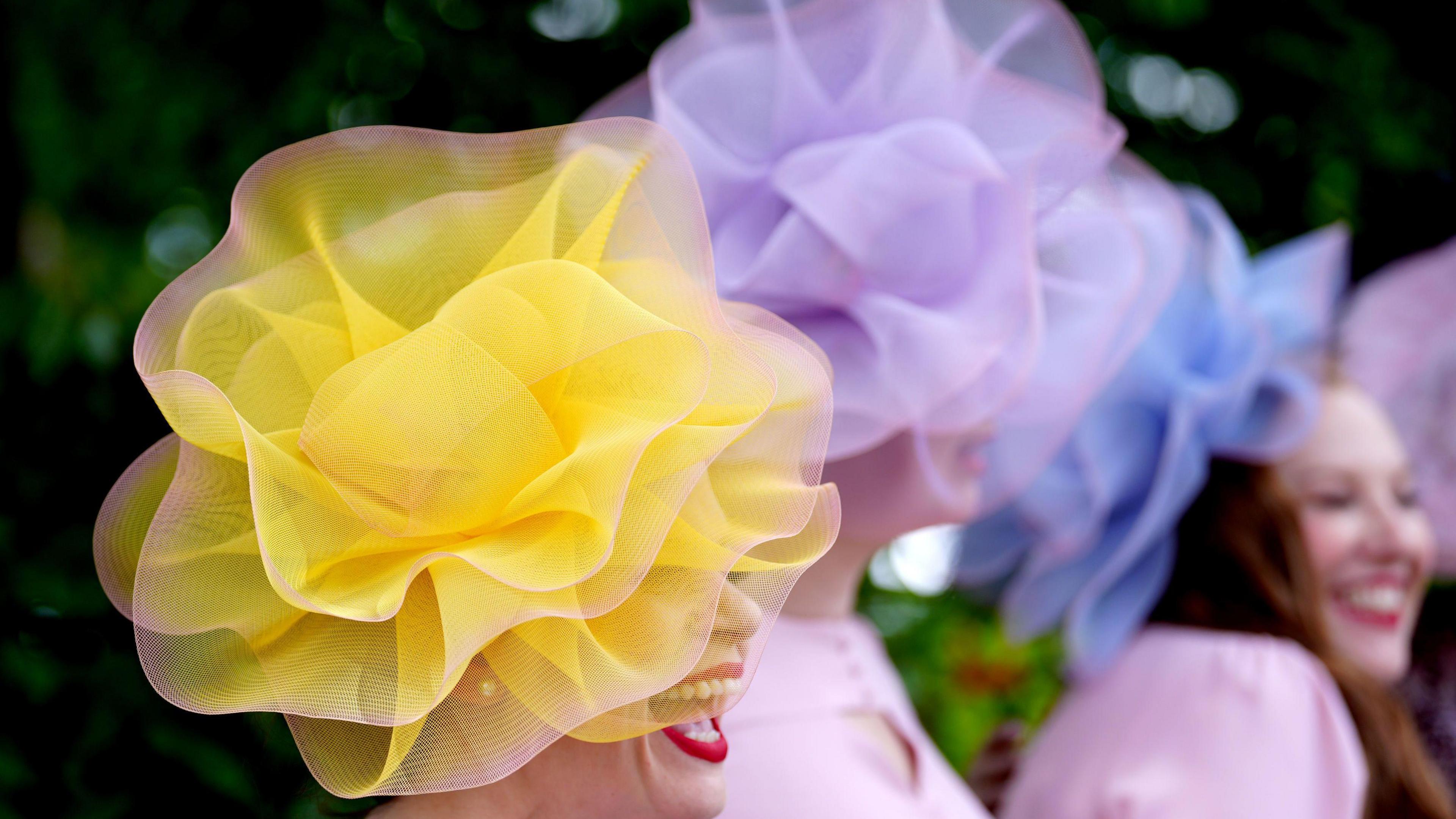 Racegoers wearing yellow and lilac pom pom style hats 