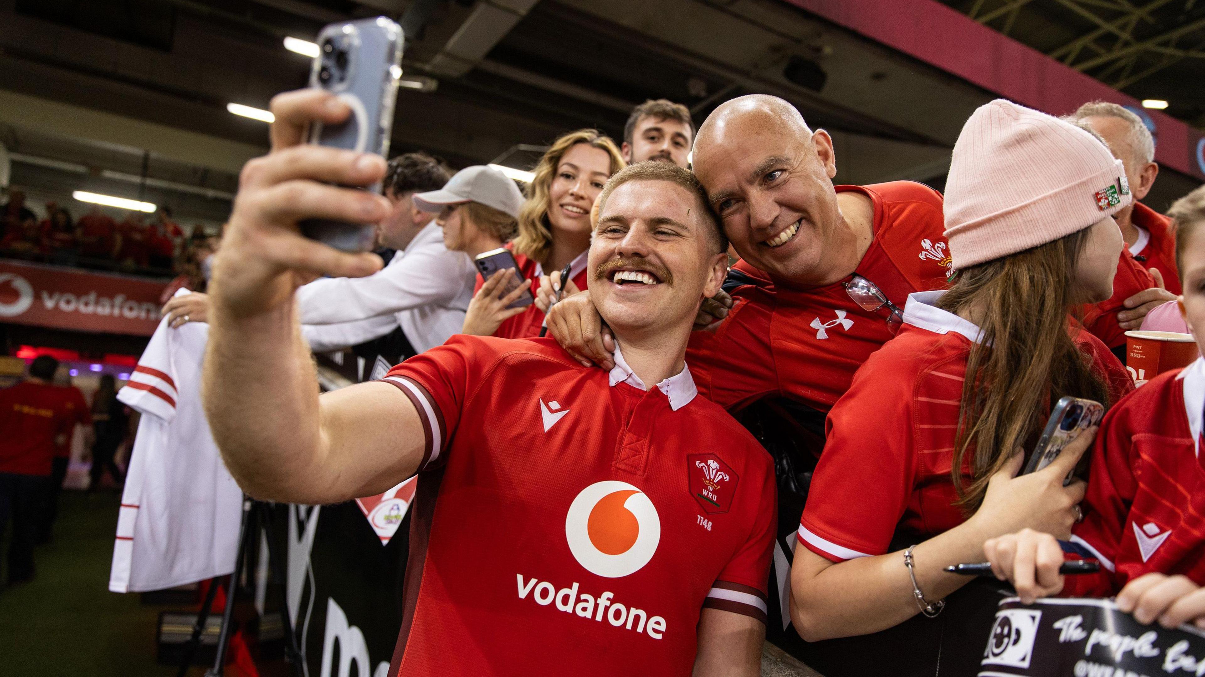 Aaron Wainwright holds a mobile phone to take a selfie with a Wales supporter