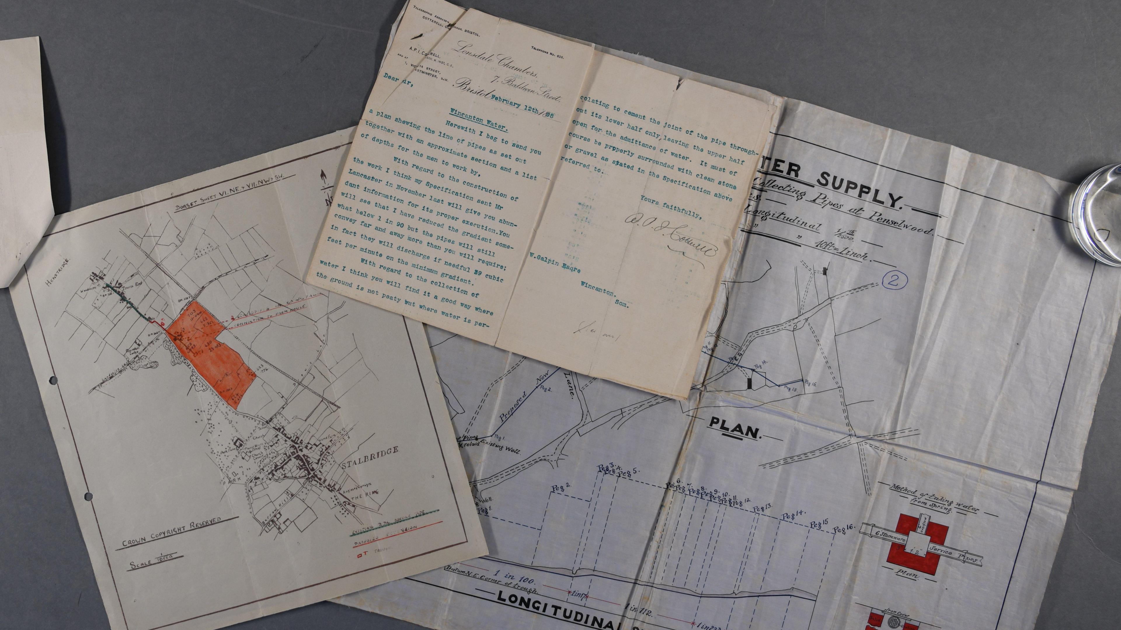 Three separate documents laid atop one another. Two are maps and they are all from the Wessex water archive