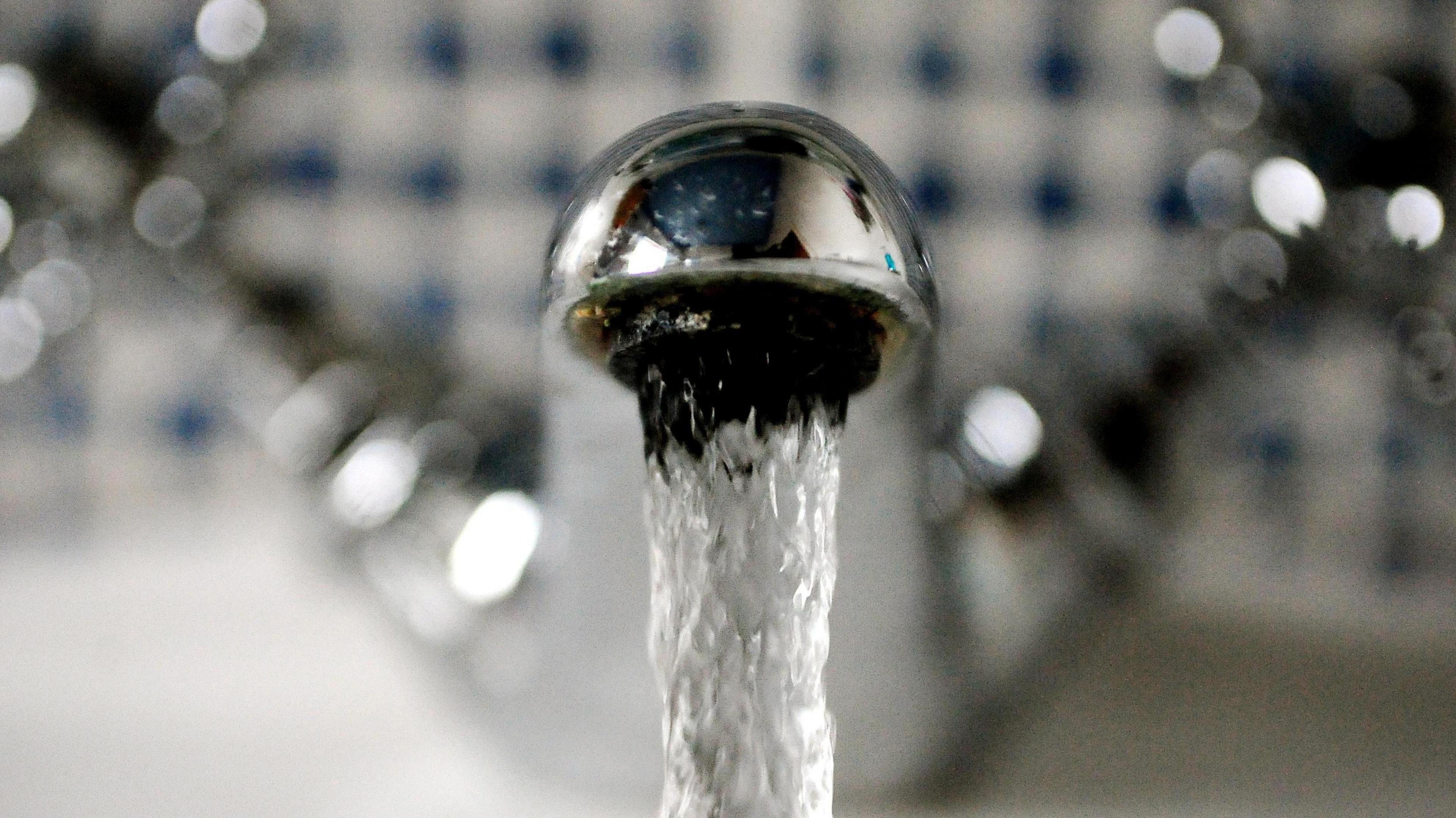 A tap has running water coming out of it. It is a silver tap with clear water.