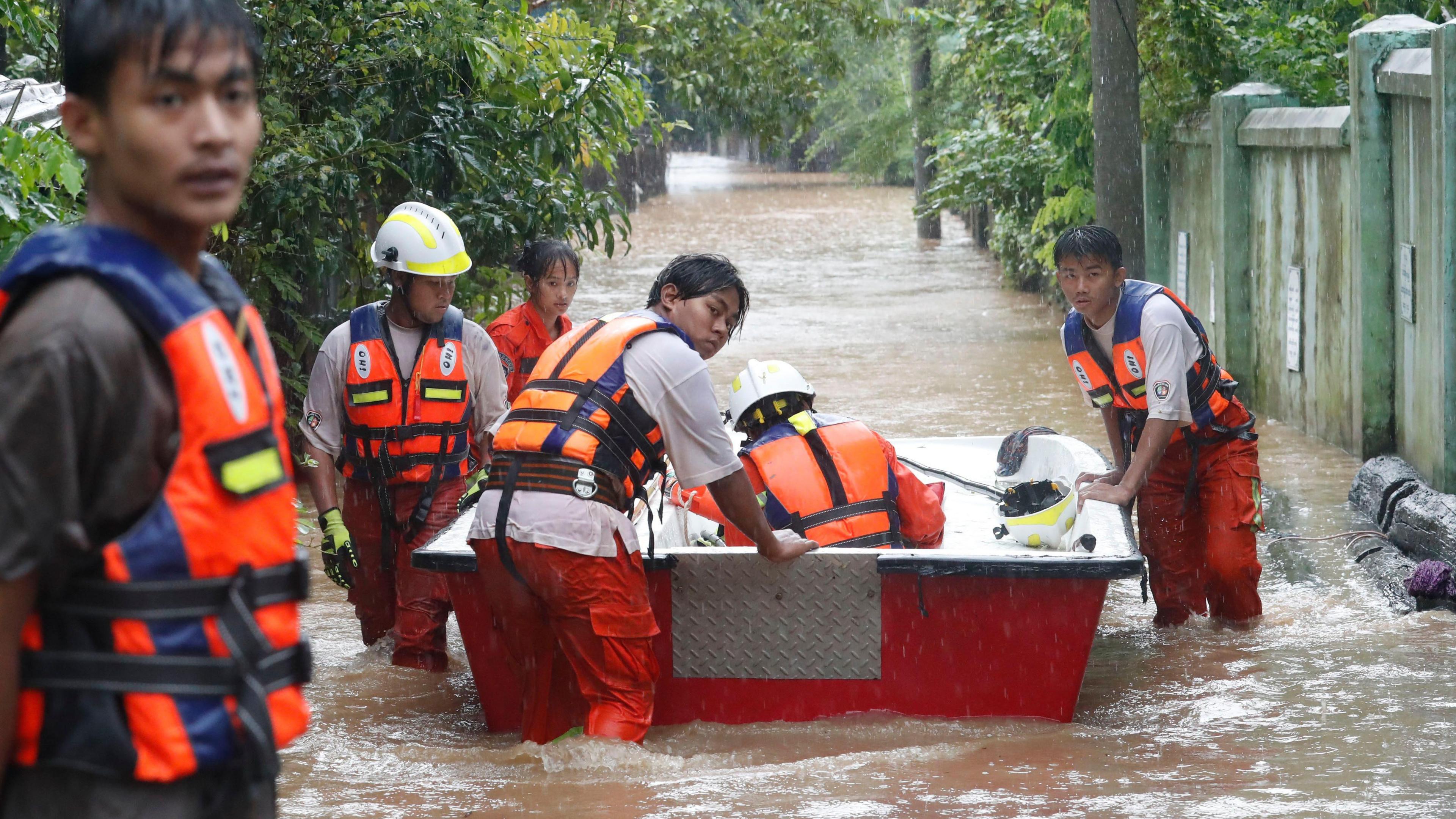 Rescue volunteers with a boat wade through a flooded road in Taungoo, Myanmar, on 12 September 2024, amid heavy rains triggered by Typhoon Yagi.