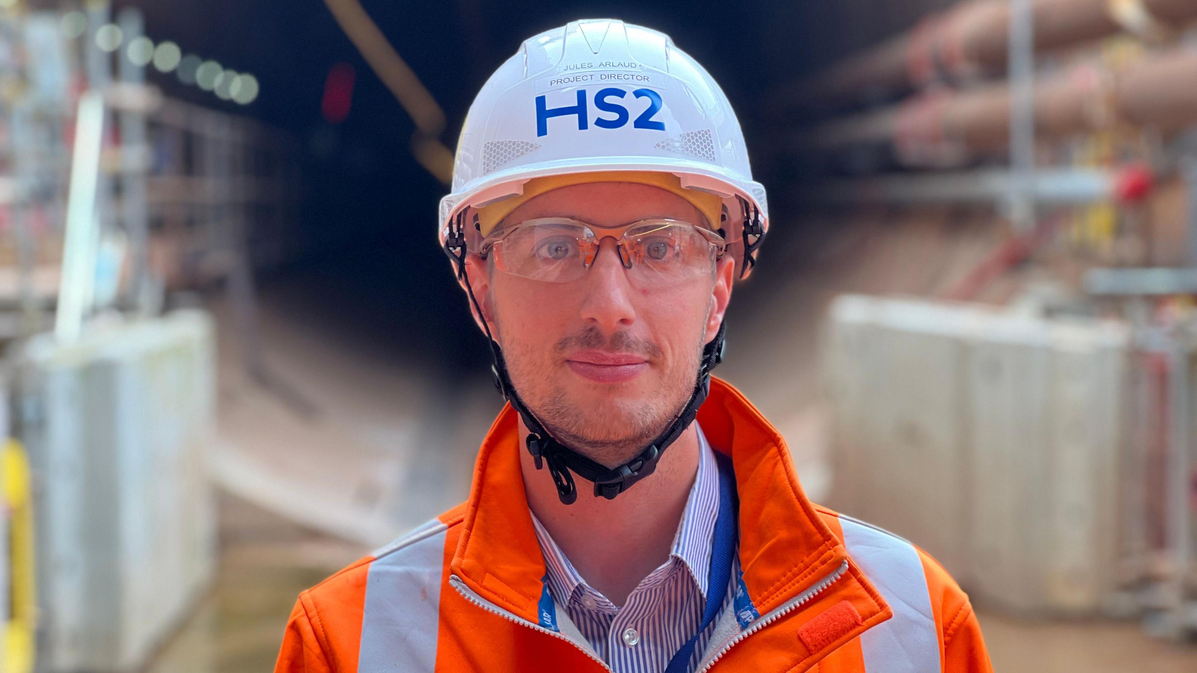 A man in a white hard hat branded HS2 on a tunnel building site