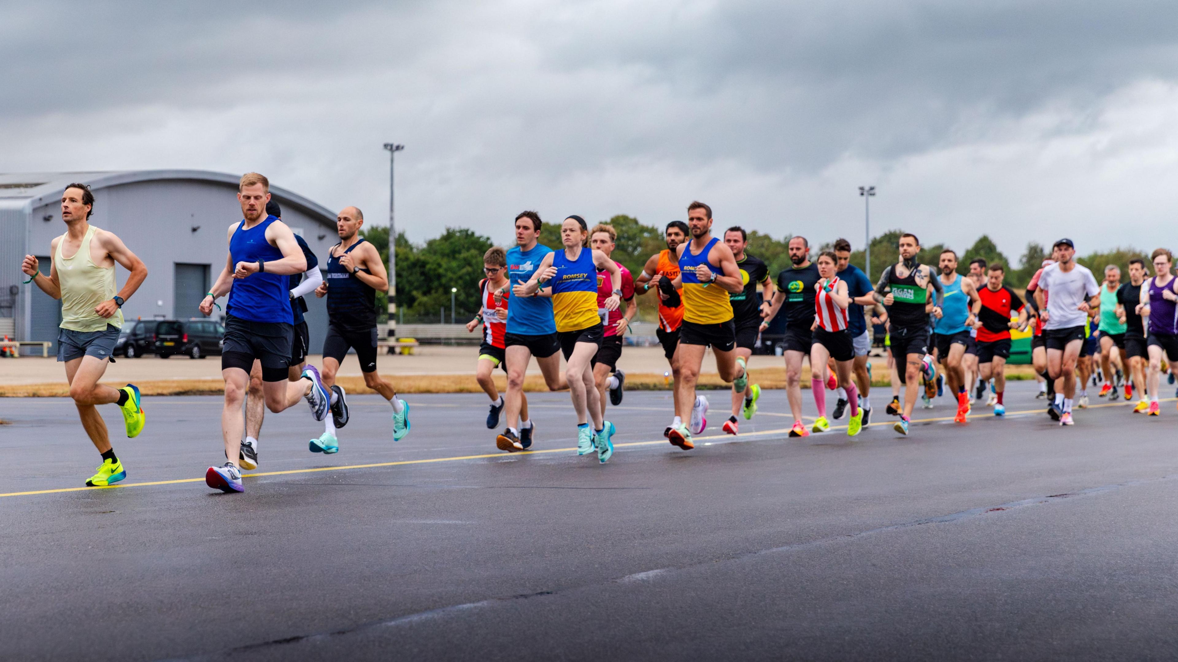 A group of runners running on a airfield runway
