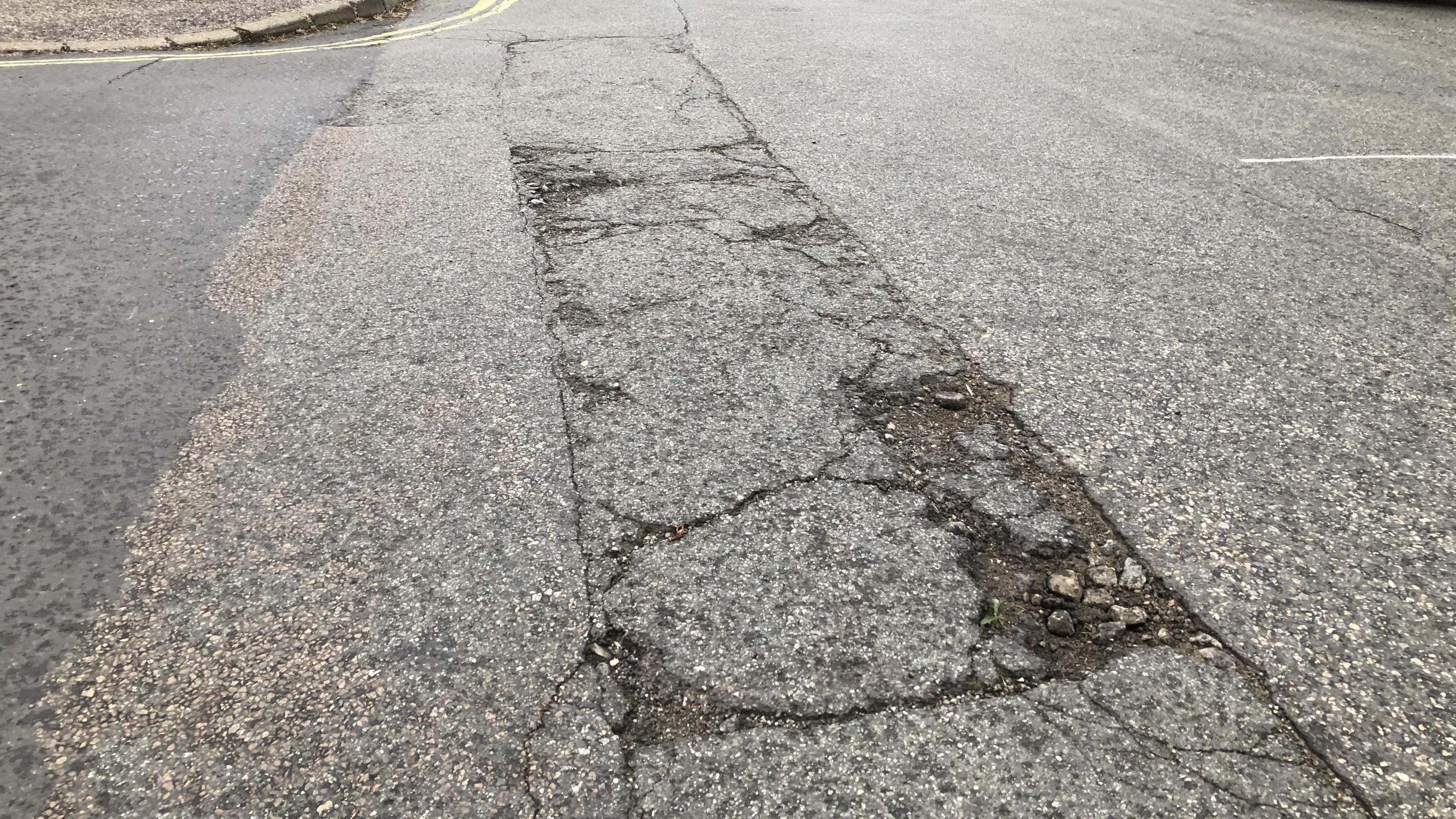 A general view of part of Devonshire Road where the road has been damaged. Cracks in the road can be seen as well as a small pothole.