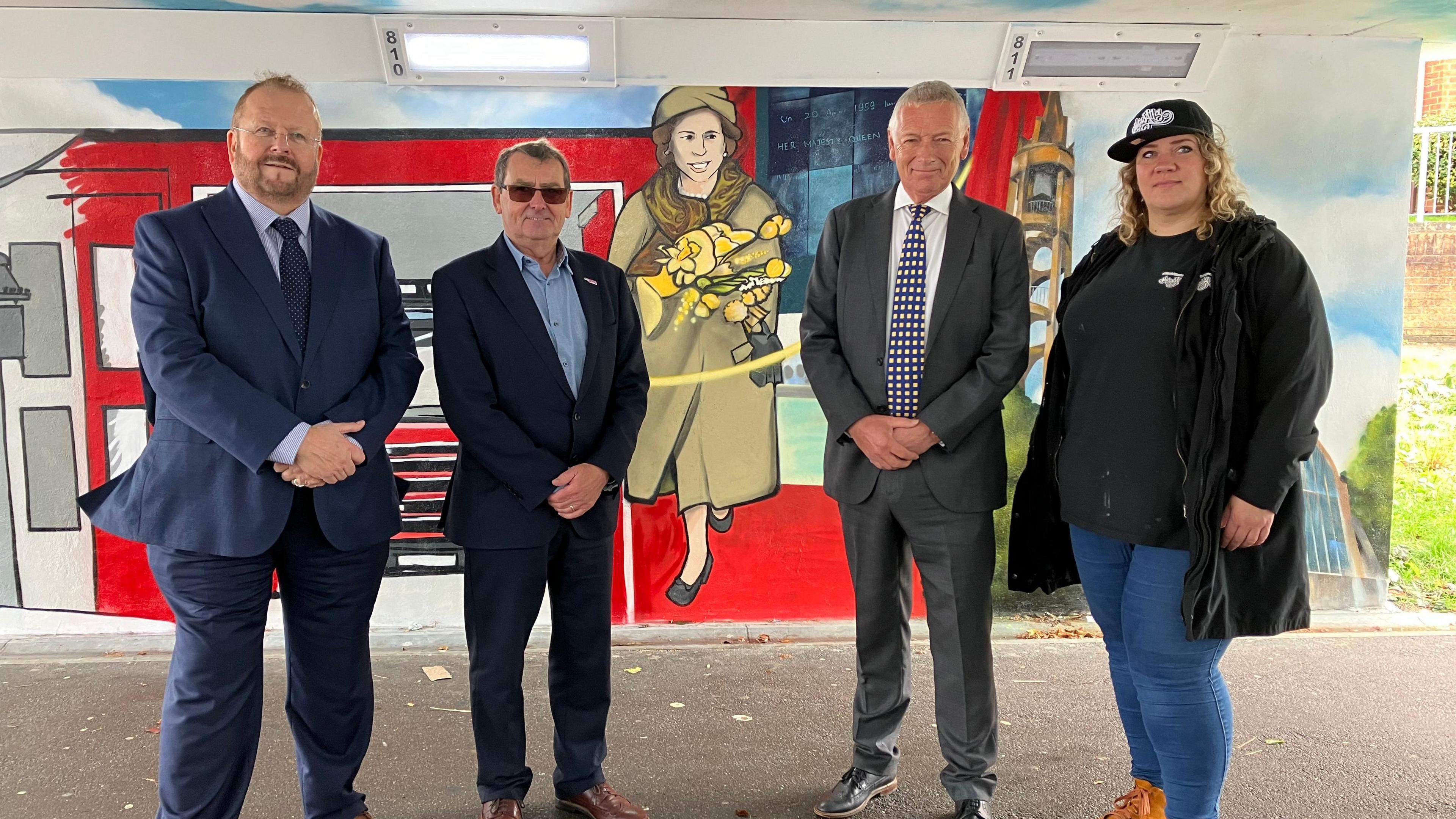 A picture of Adrian Hawkins, Cllr Richard Henry, Cllr Phil Bibby and street artist Szylk Wane in front of a part of the mural depicting the Queen's visit to Stevenage in 1959.