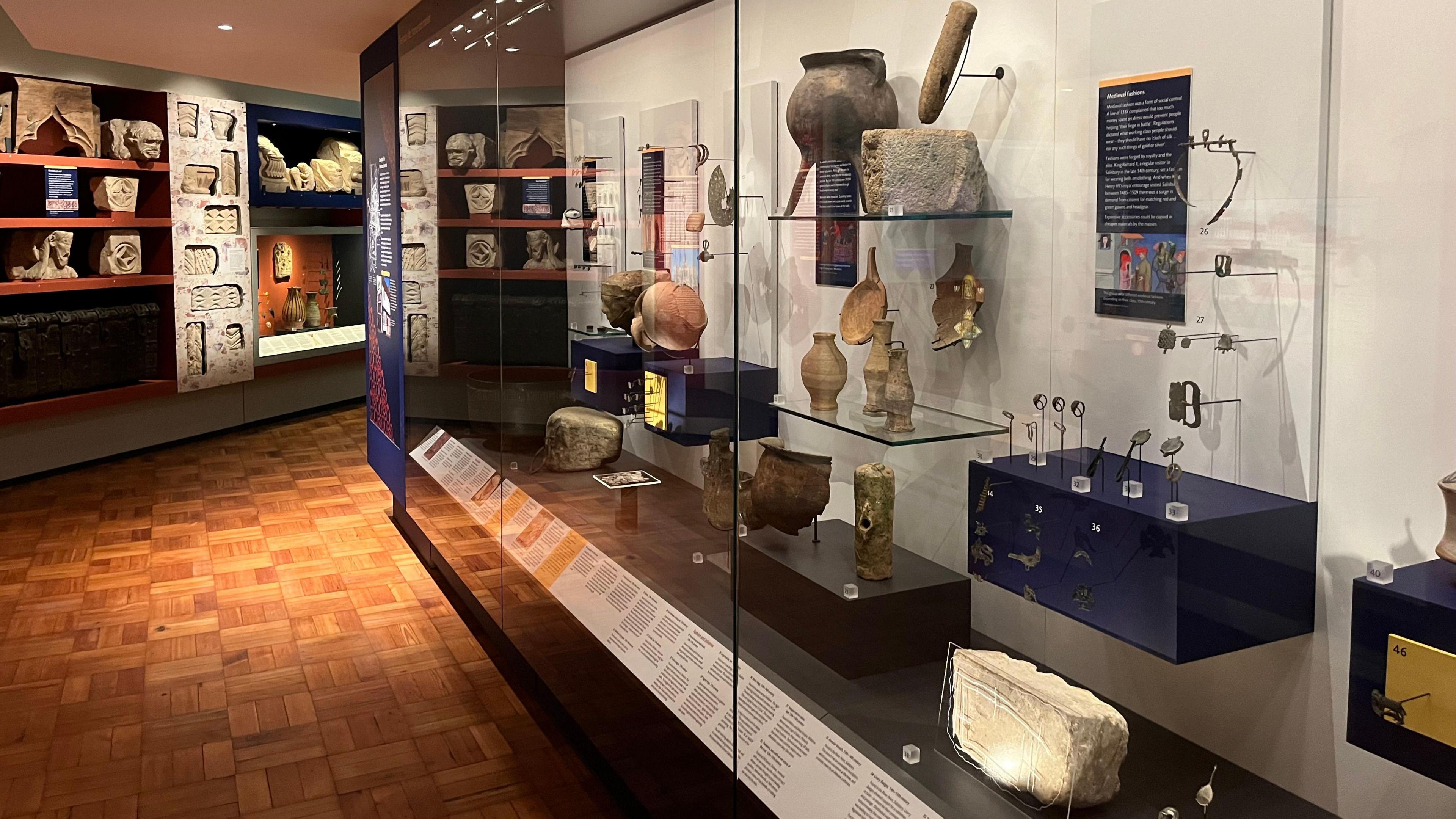 Floor to ceiling display cabinets with spotlights and old objects