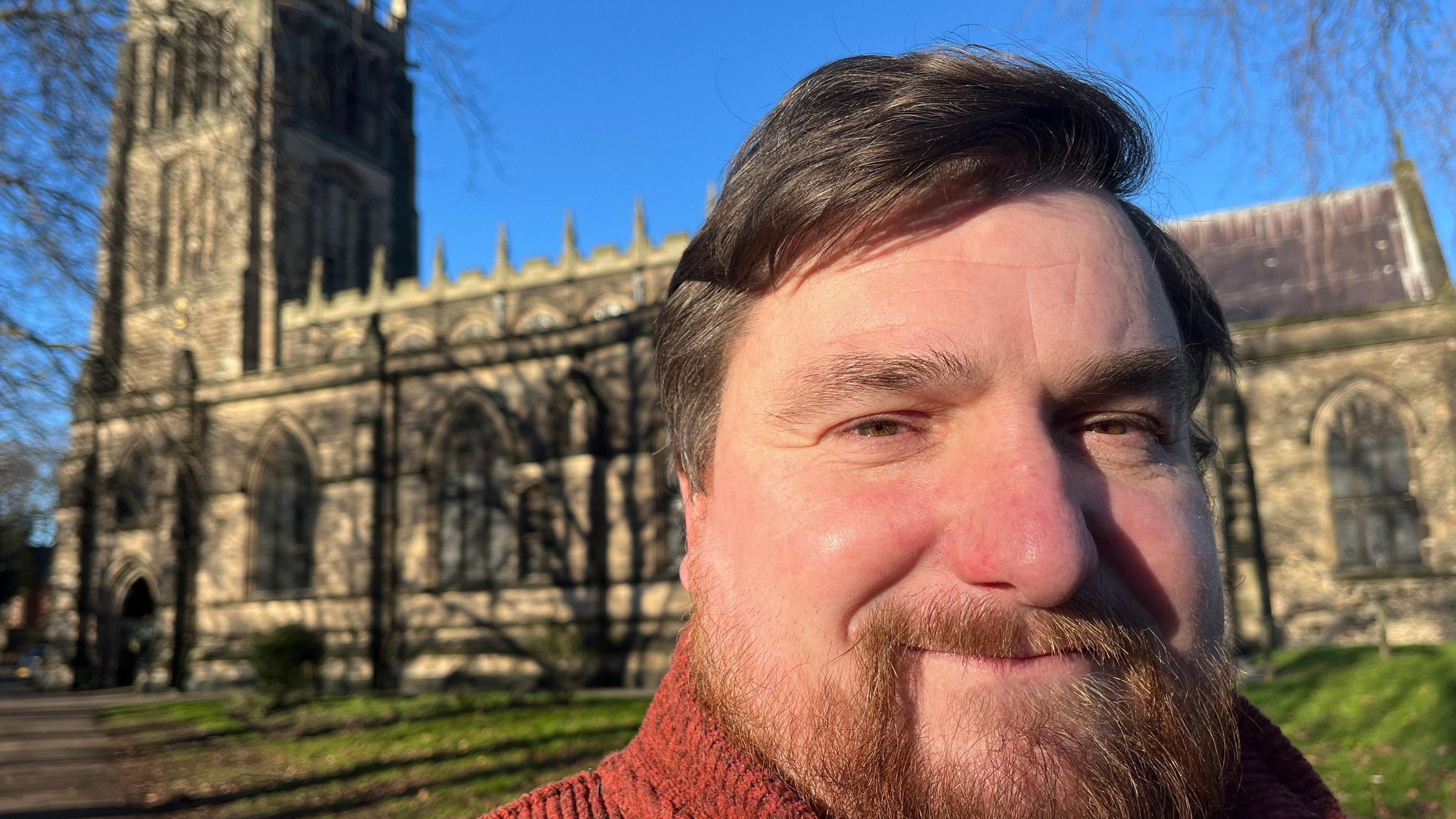 A close up of Andy Clarke's face with All Saints Church in the background
