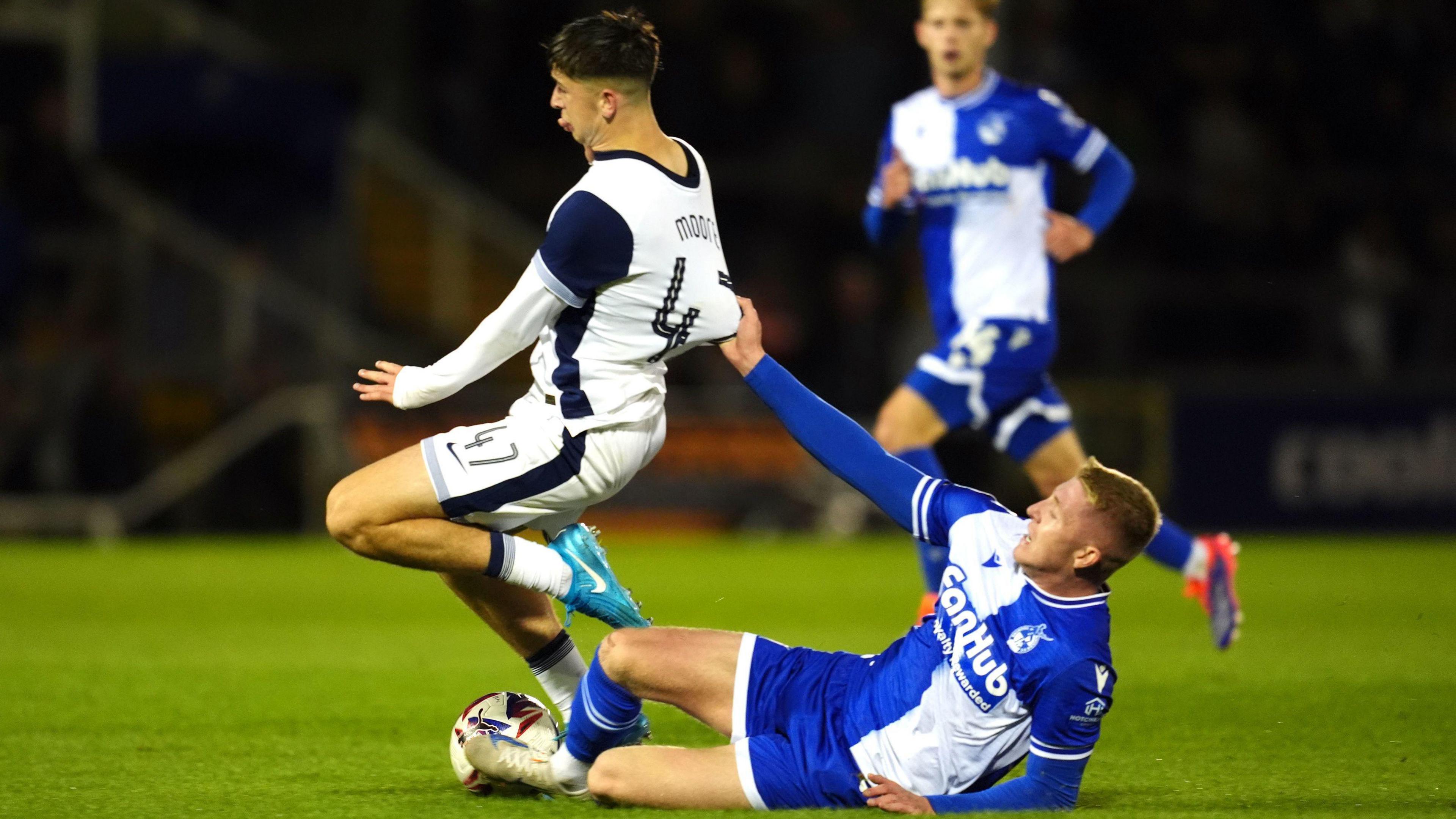 Tottenham Hotspur's Mikey Moore is challenged by Bristol Rovers' Joel Senior during the Bristol Street Motors Trophy match at the Memorial Stadium. Joel Senior is lying on the pitch and holding on to Mikey Moore's shirt