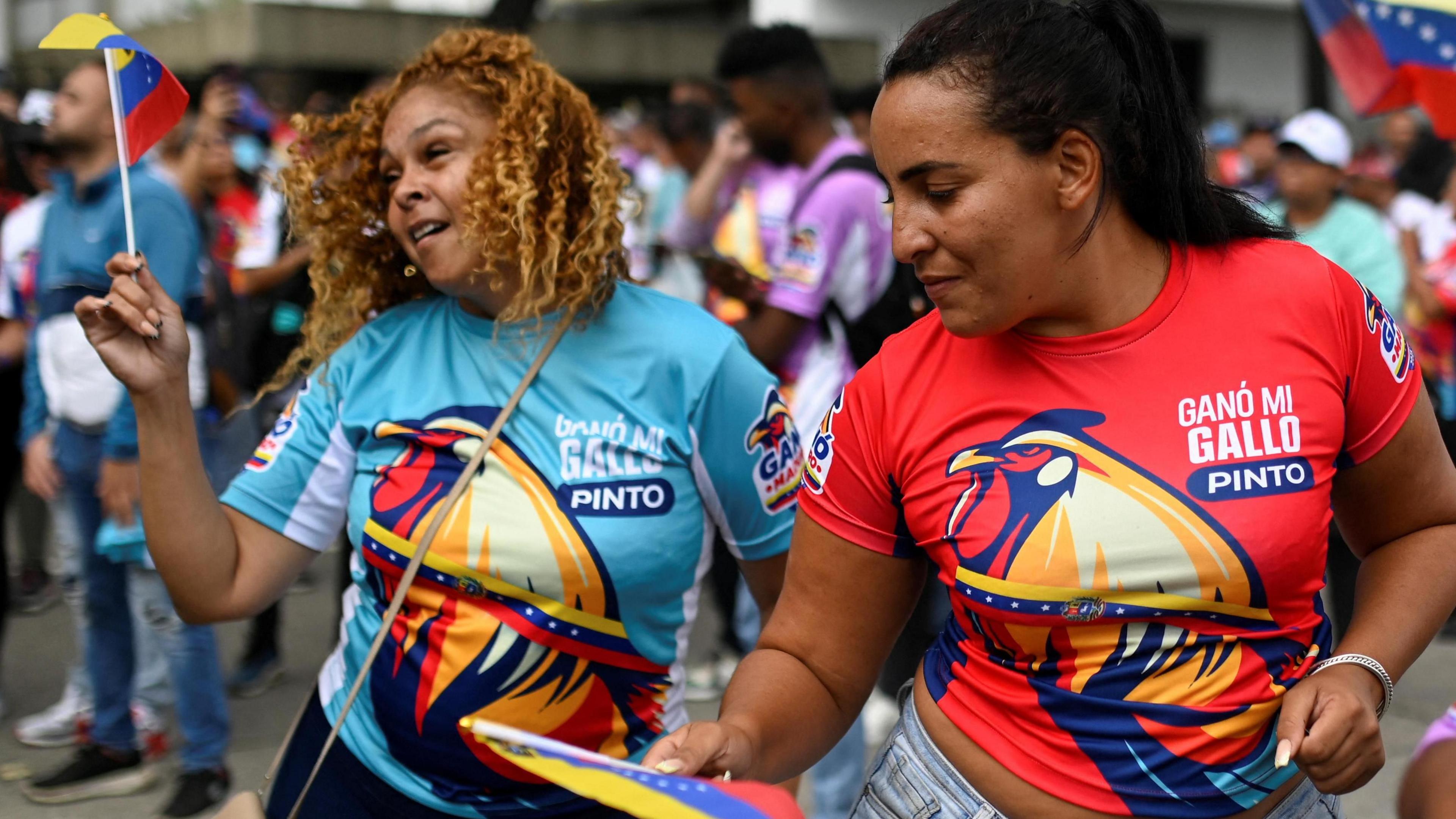 Two women dancing and waving flags in support of Venezuela's President Nicolas Maduro