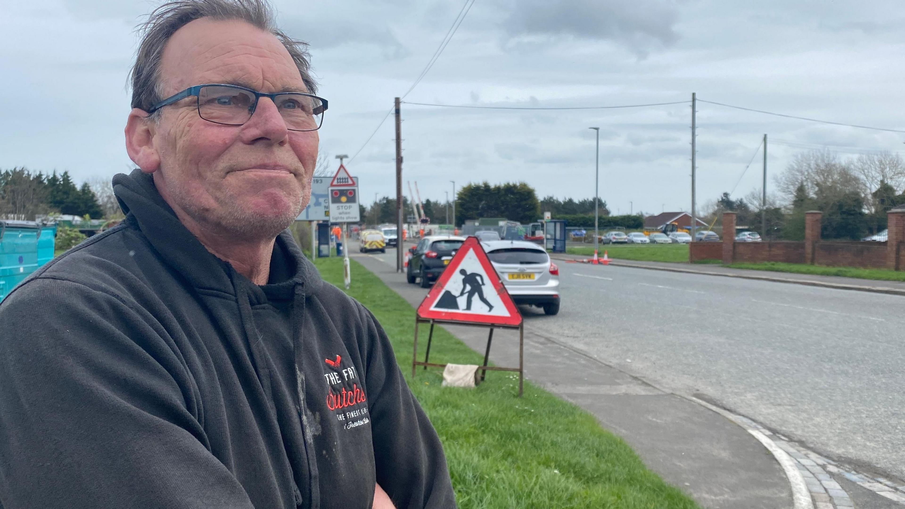 A man standing near a level crossing with his arms folded 