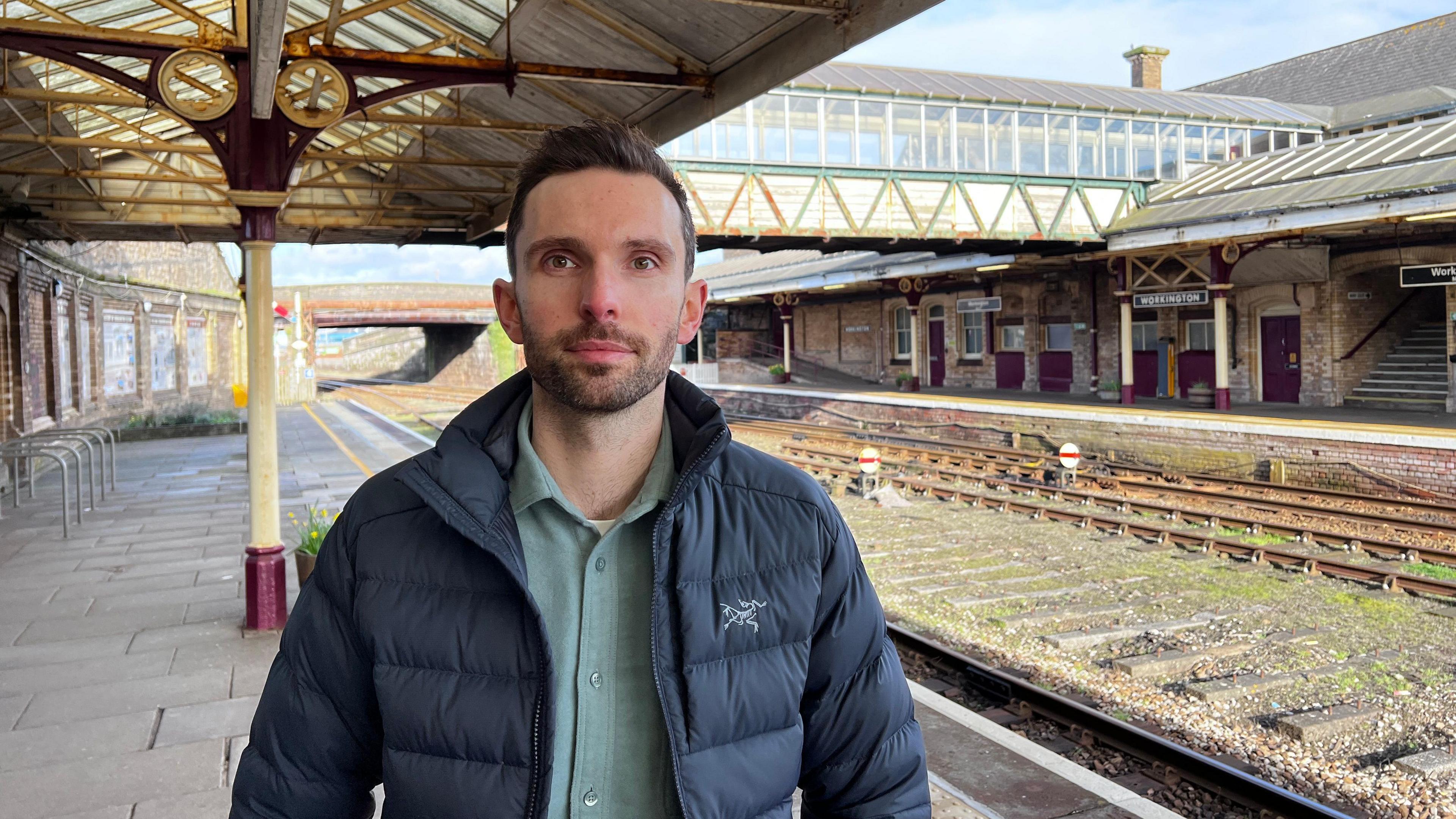 Josh MacAlister at Workington train station with the tracks behind him