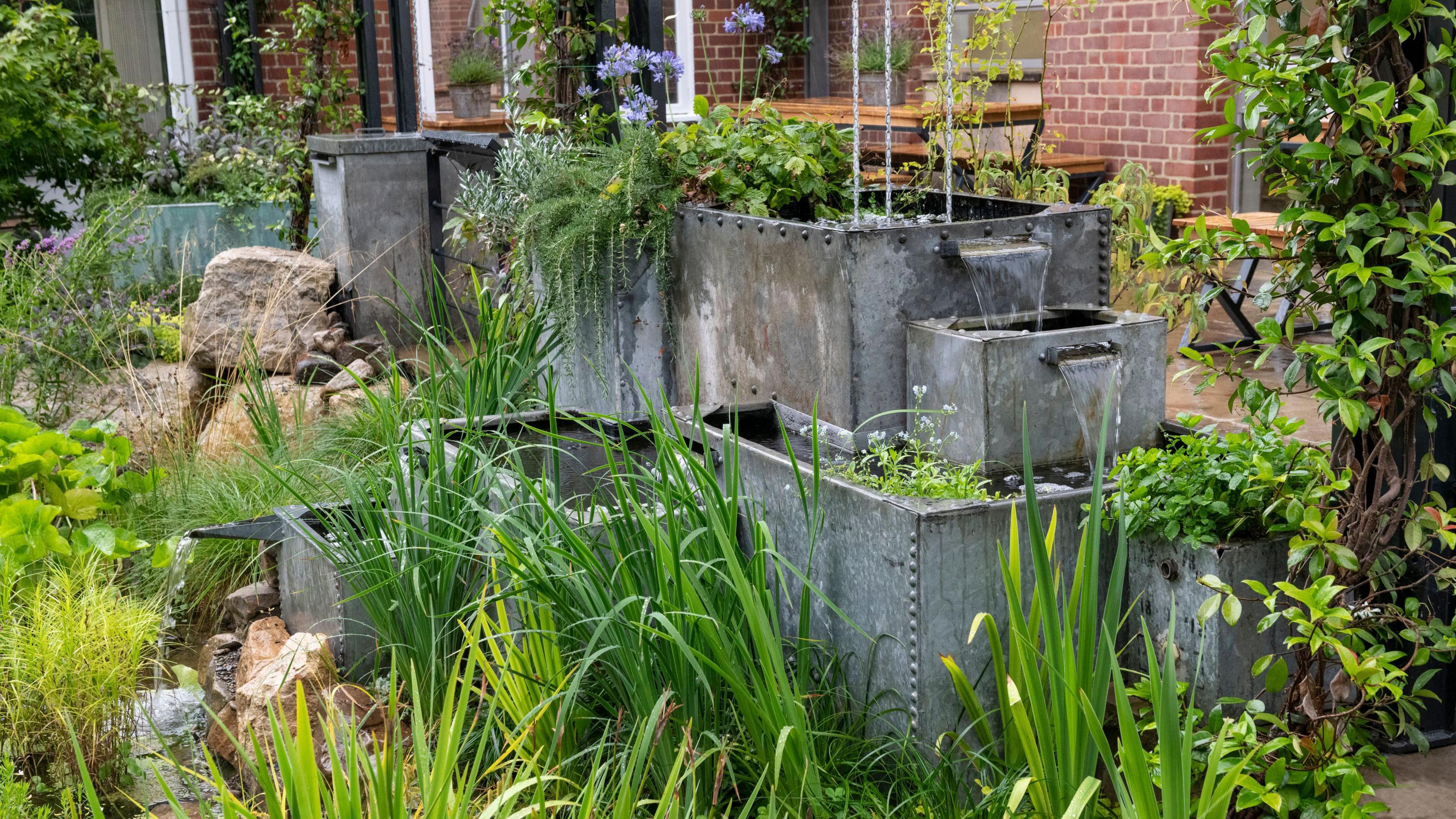Recycled galvanised watertank water features with waterfalls and rain chains, which help slow and manage the flow of rainwater into the garden, in the Flood Resilient Garden at Howbery Park in Wallingford, Oxfordshire.
