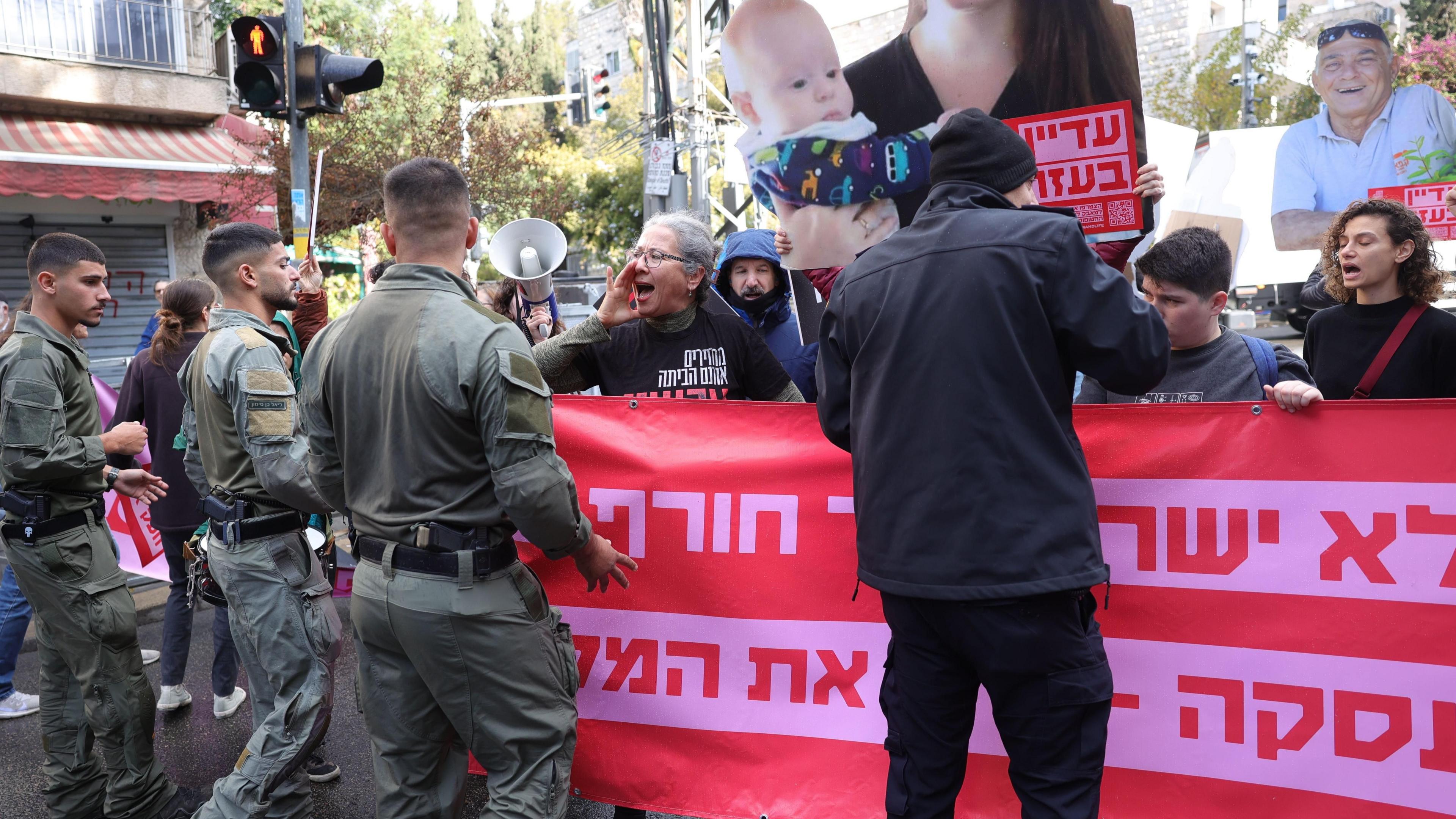 Relatives of Gaza hostages protest behind large banner in Hebrew, as Israeli police face them outside the Israeli prime minister's office in Jerusalem