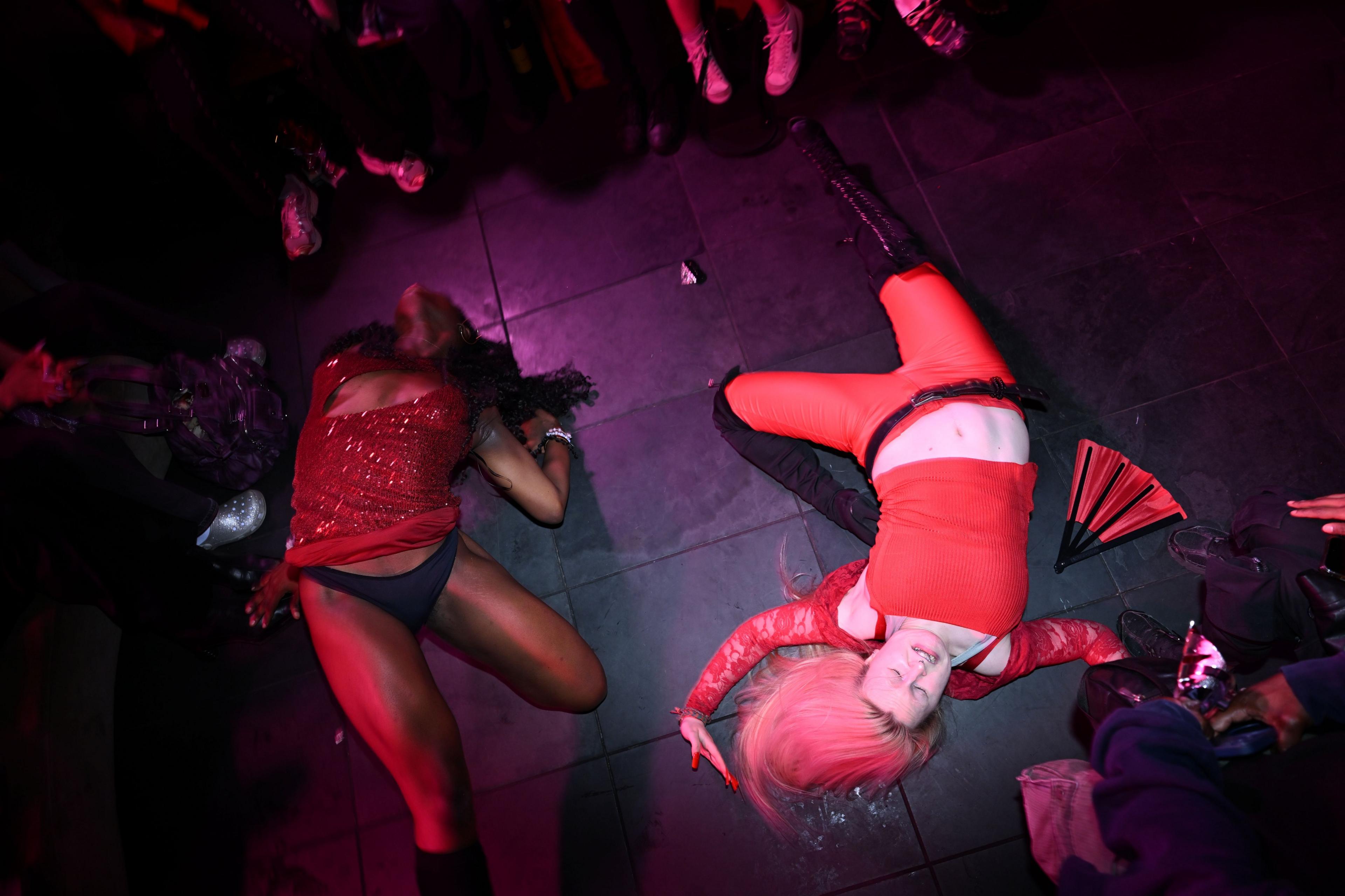 Performers vogue at the centre of the runway, lying on the floor with their eyes closed as spectators cheer around them.