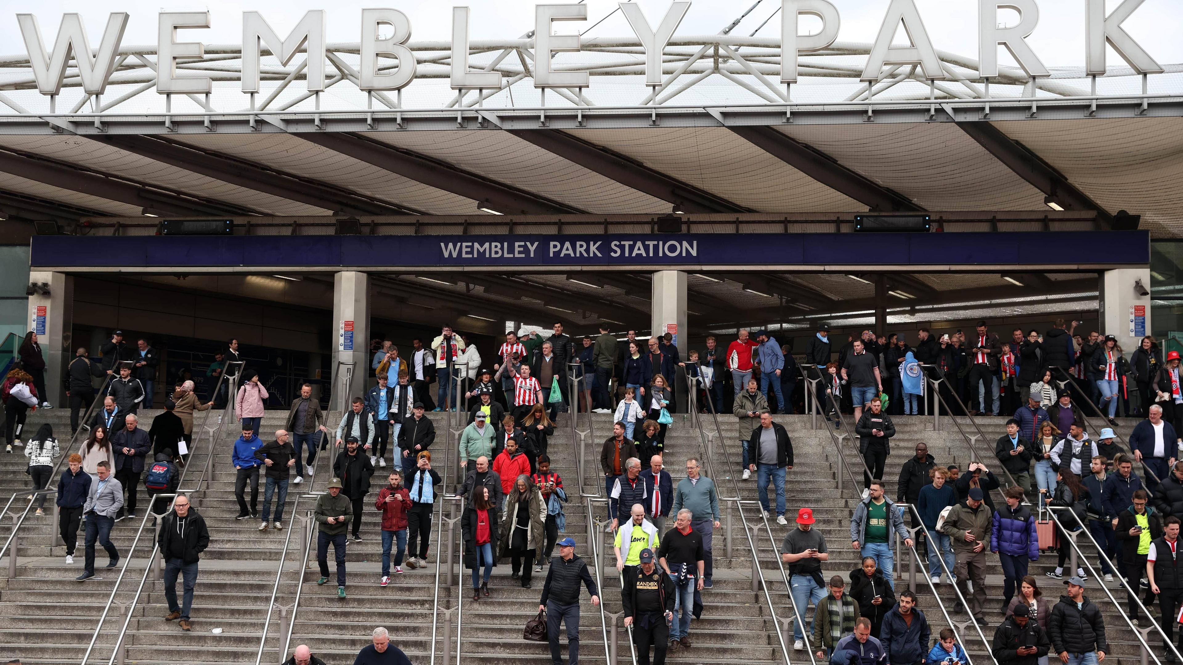 Dozens of football fans make their way down steps at Wembley Park Station.