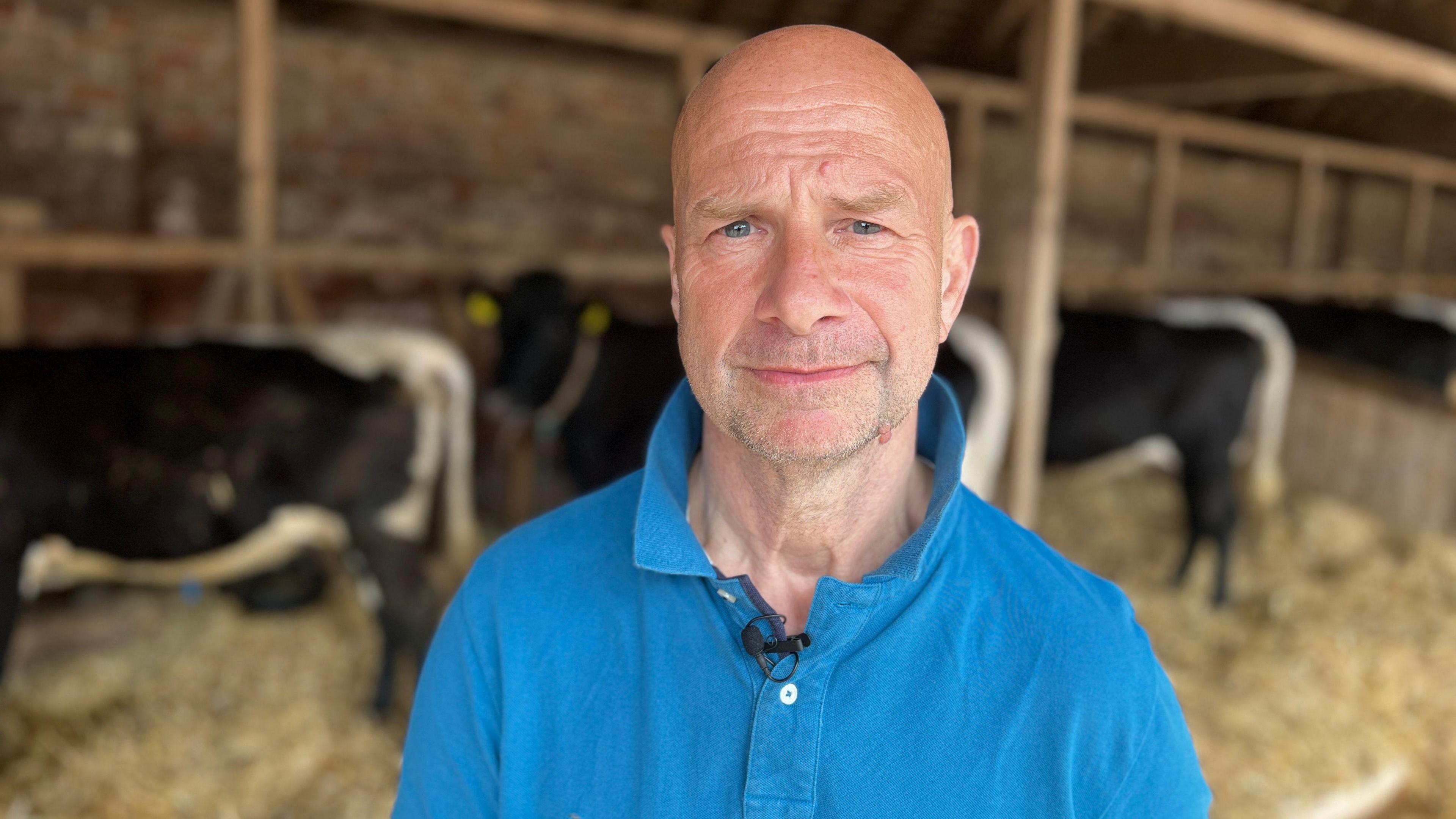 Clifford Freeman wearing a blue polo shirt, standing in a cattle barn