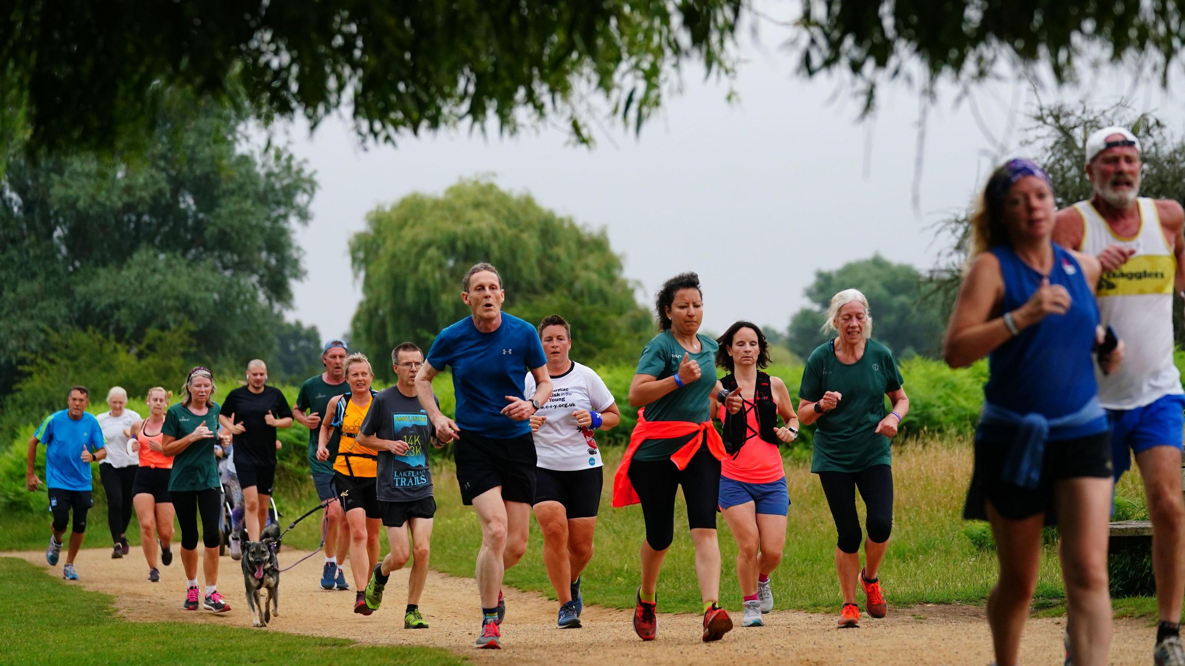 A group of runners going down a track in a park