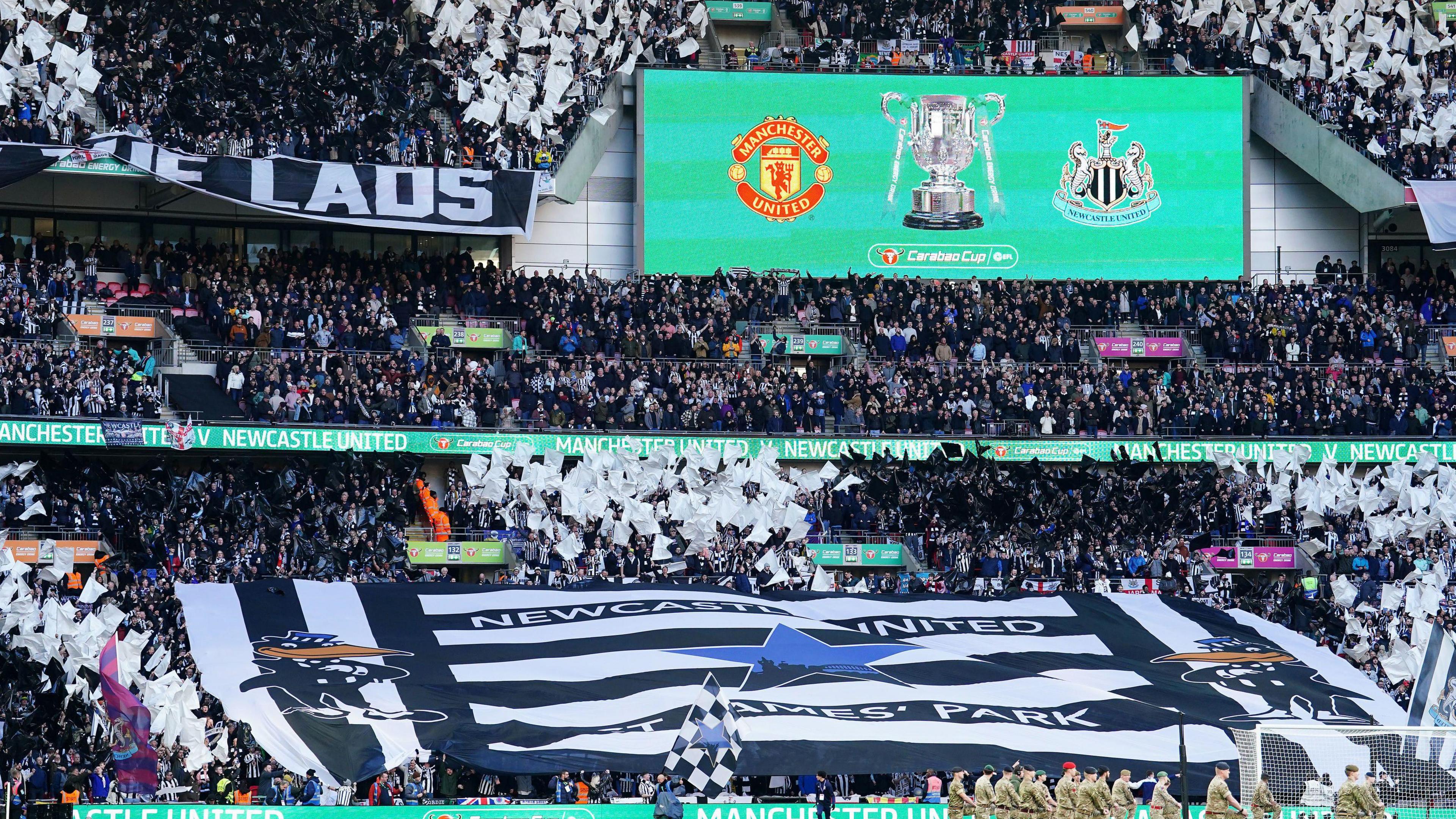 Newcastle United fans inside Wembley Stadium in 2023. The stand is covered in a big black and white Newcastle United flag.