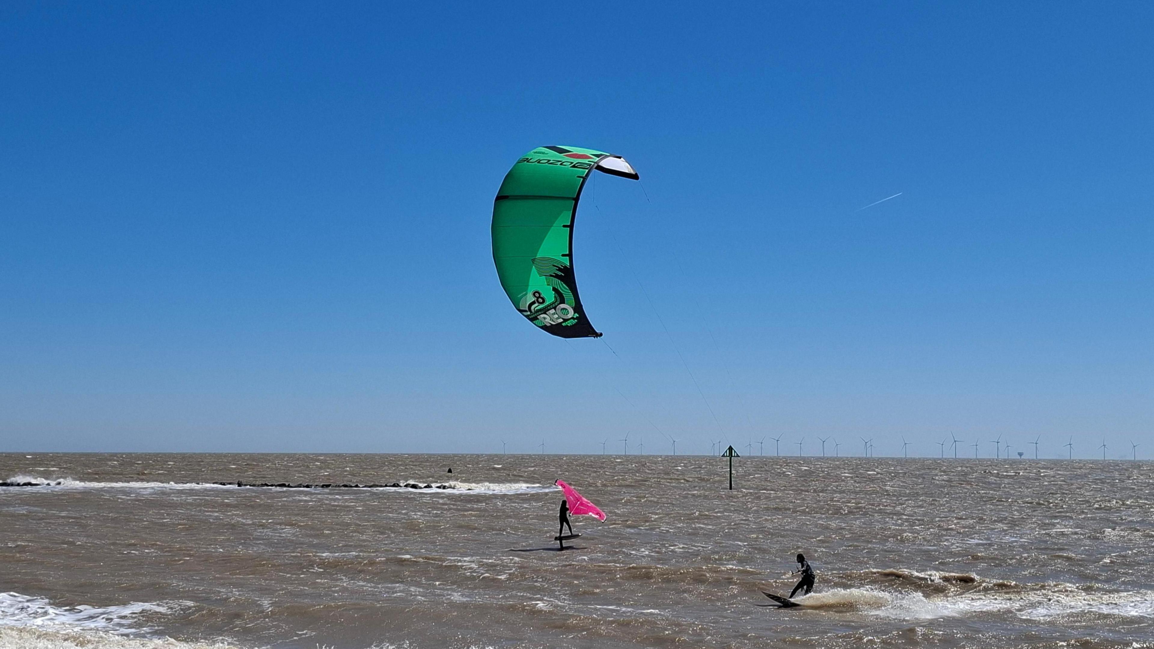 Sunny, blue skies by the beach with kite surfers in Essex