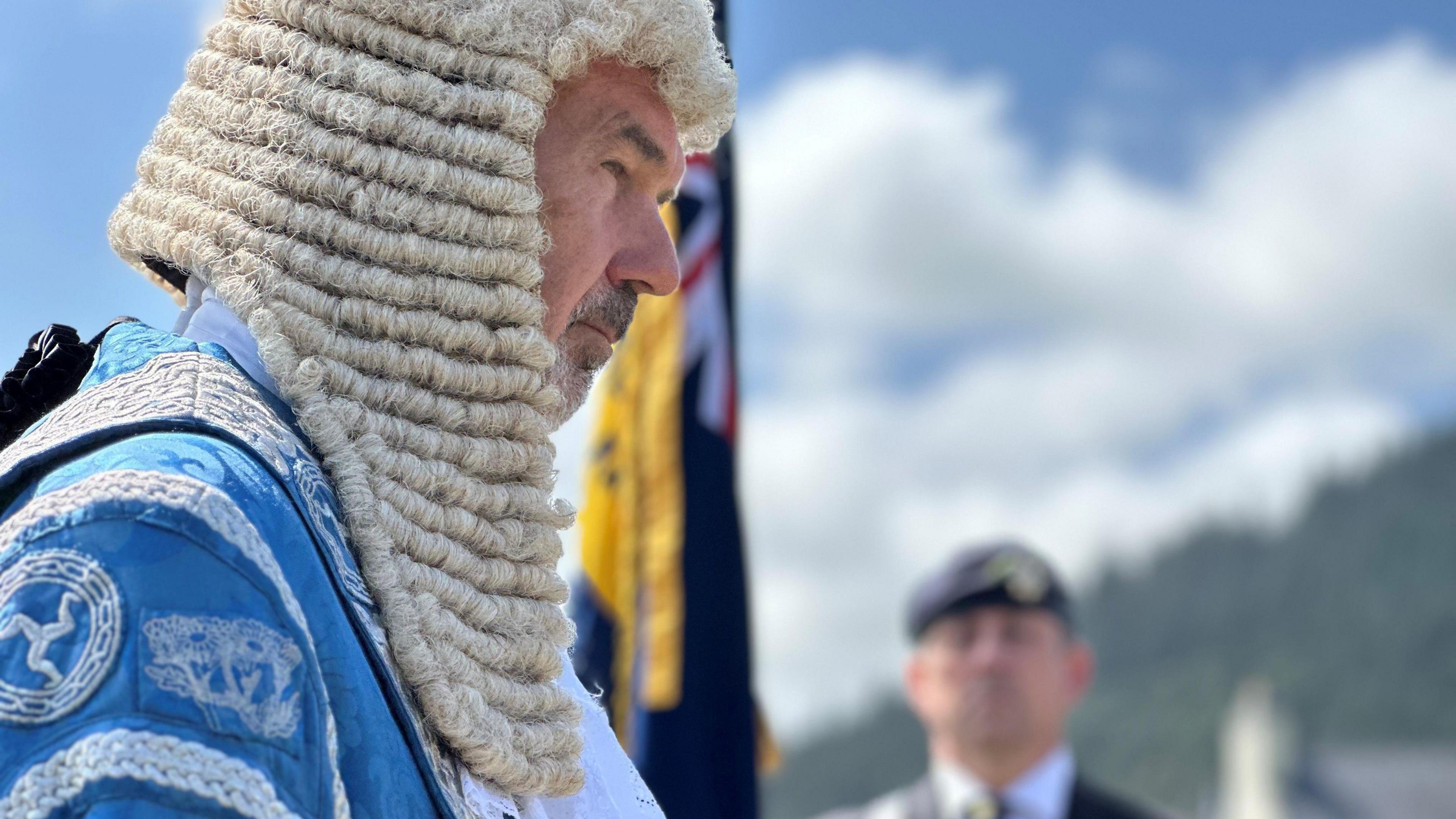 President of Tynwald Laurence Skelly wearing blue robes with silver decoration and a long white wig.