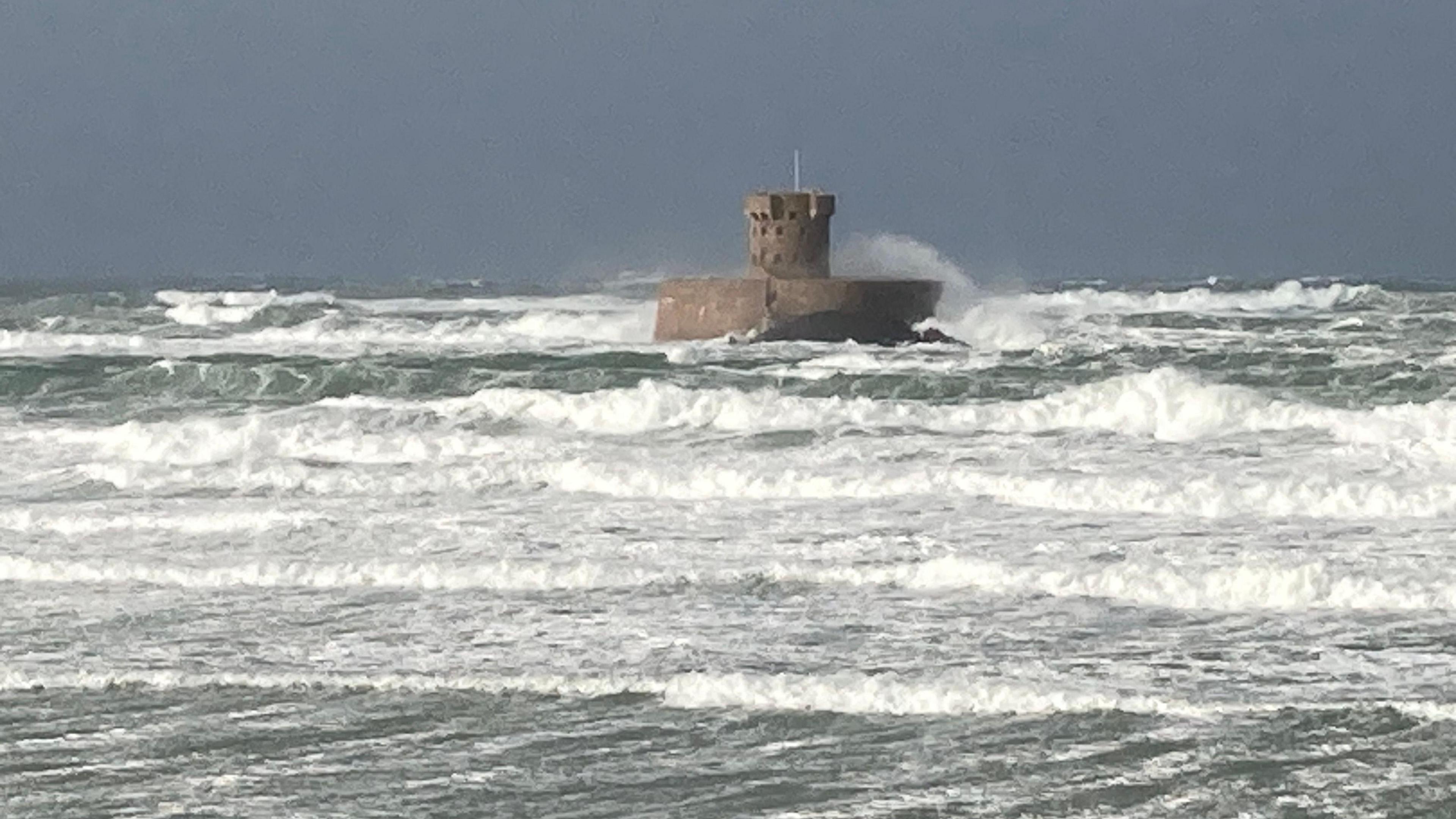 Waves hit La Rocco Tower - a stone tower with castle-like crenulations at St Ouen beach, Jersey, Channel Islands on Saturday morning.