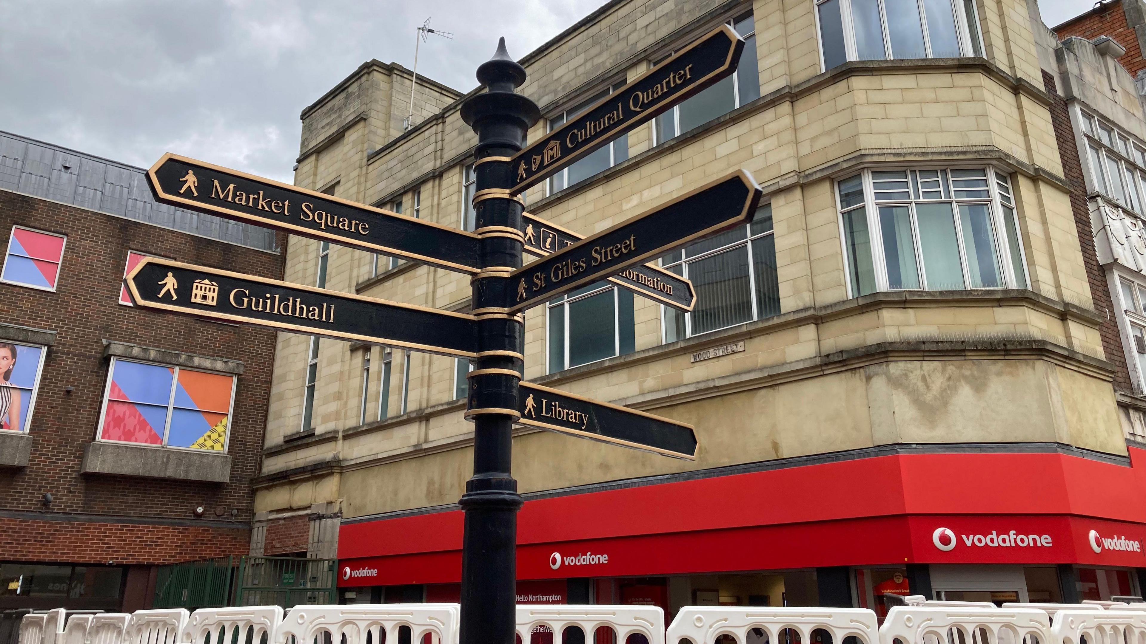 A black sign showing the direction for different parts of Northampton Town Centre. 