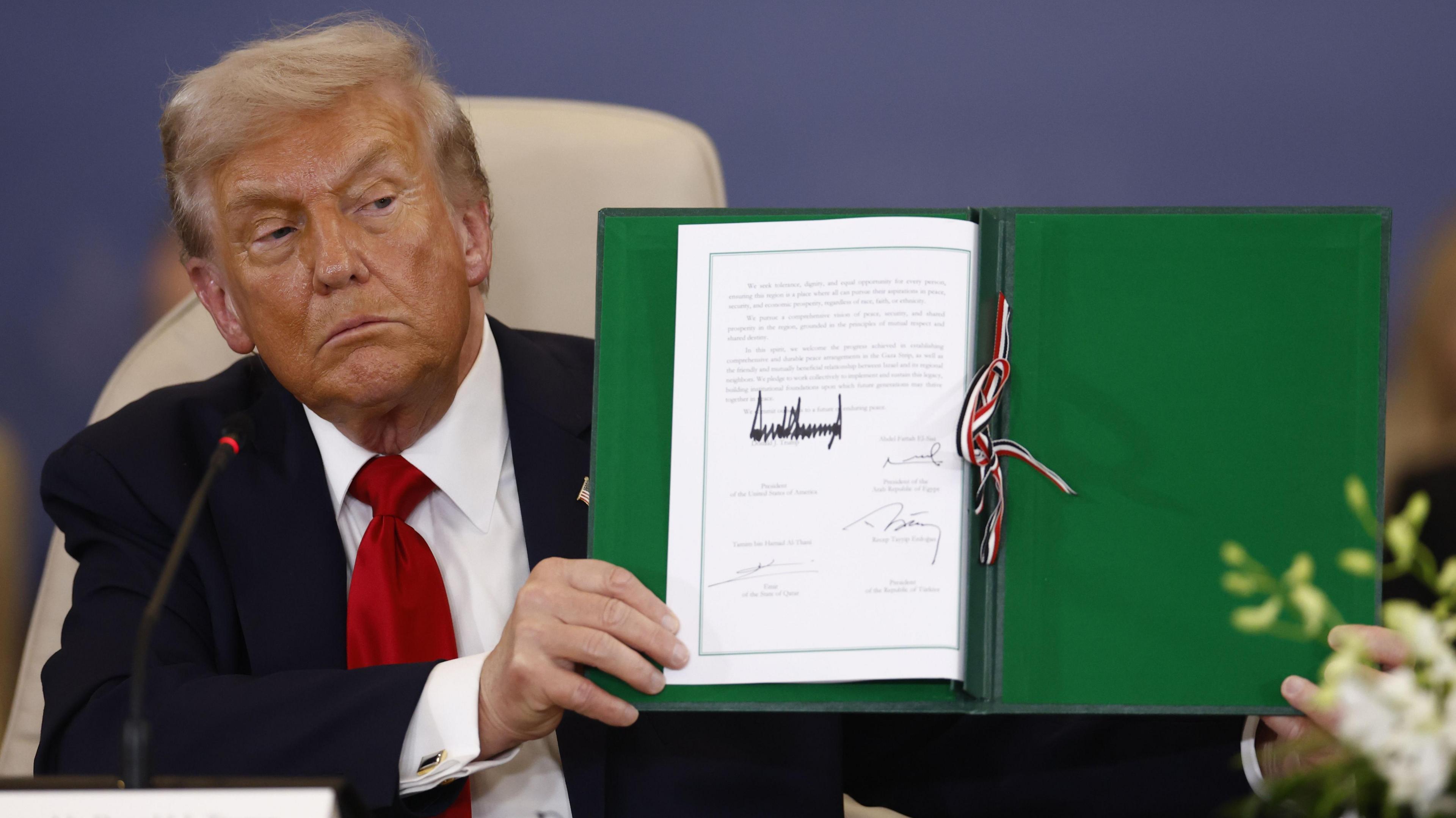 US President Donald Trump holds up a signed document at the Gaza Peace Summit in Sharm El-Sheikh, Egypt