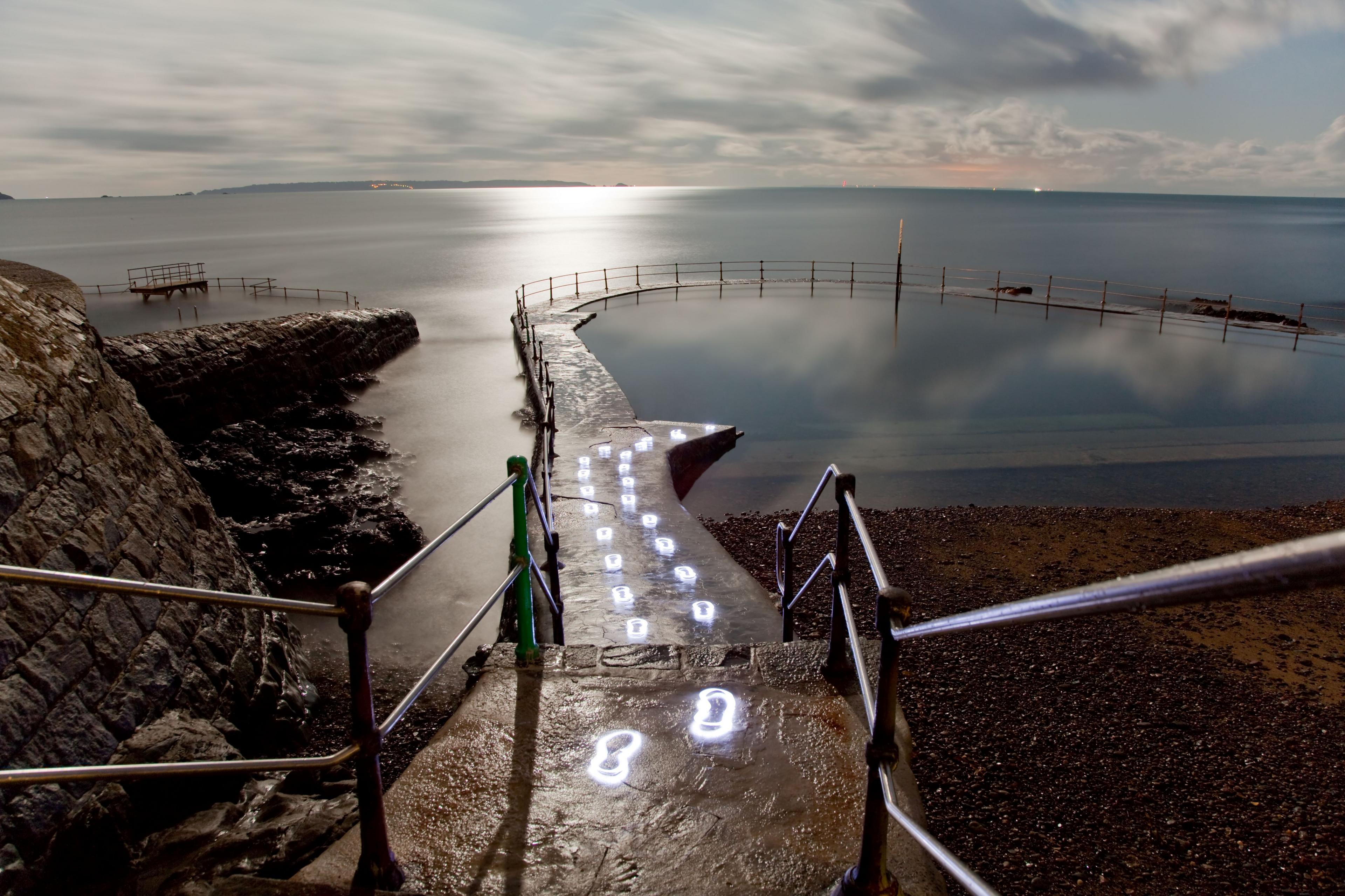 A stone walkway that curves around the loch, with illuminated foot steps curling around it. 