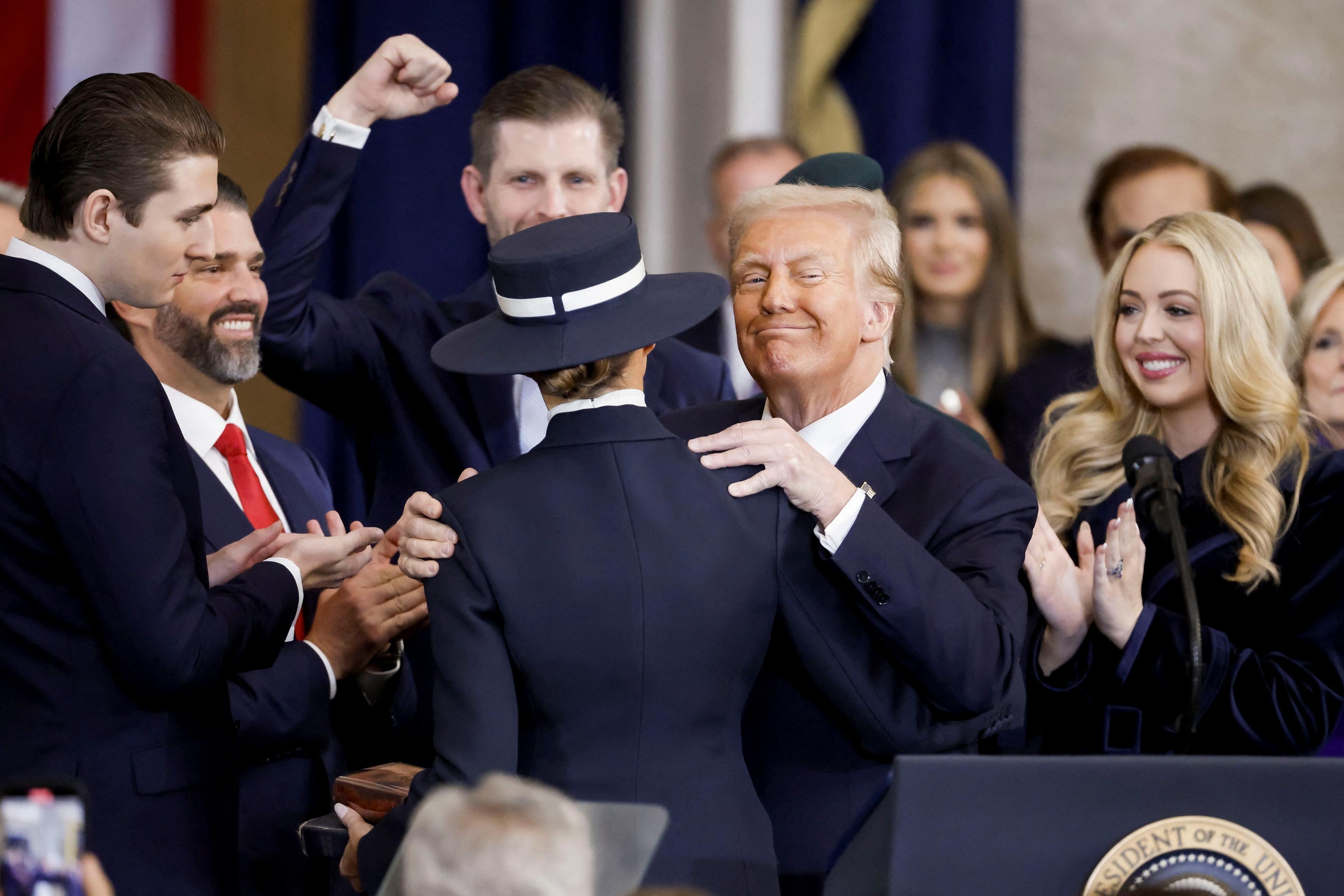 Donald Trump, smiling, embraces his wife Melania as his children Barron, Donald Jnr, Eric, and Tiffany look on