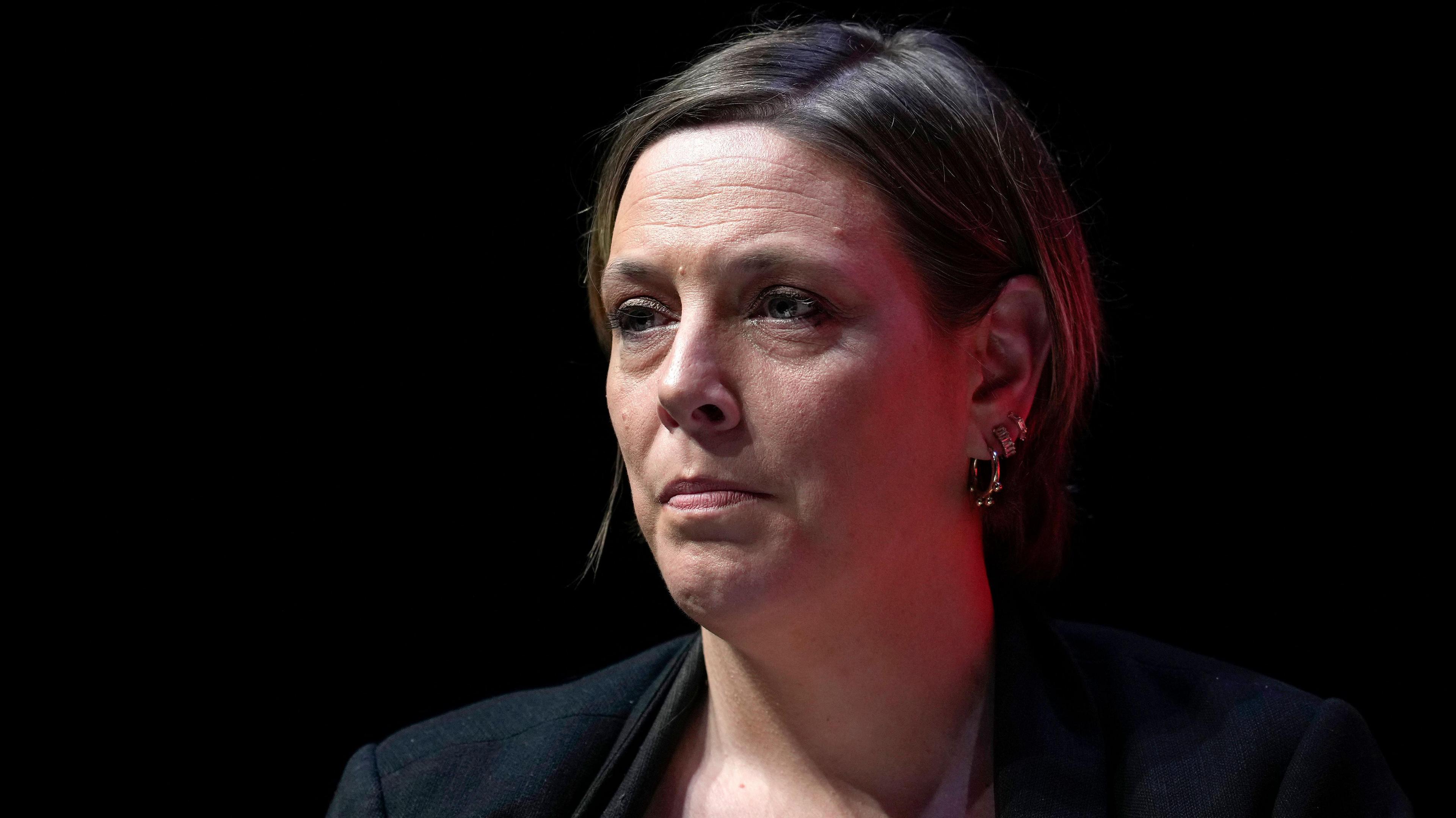Jess Phillips wearing a navy blazer and cropped hair in front of a dark backdrop
