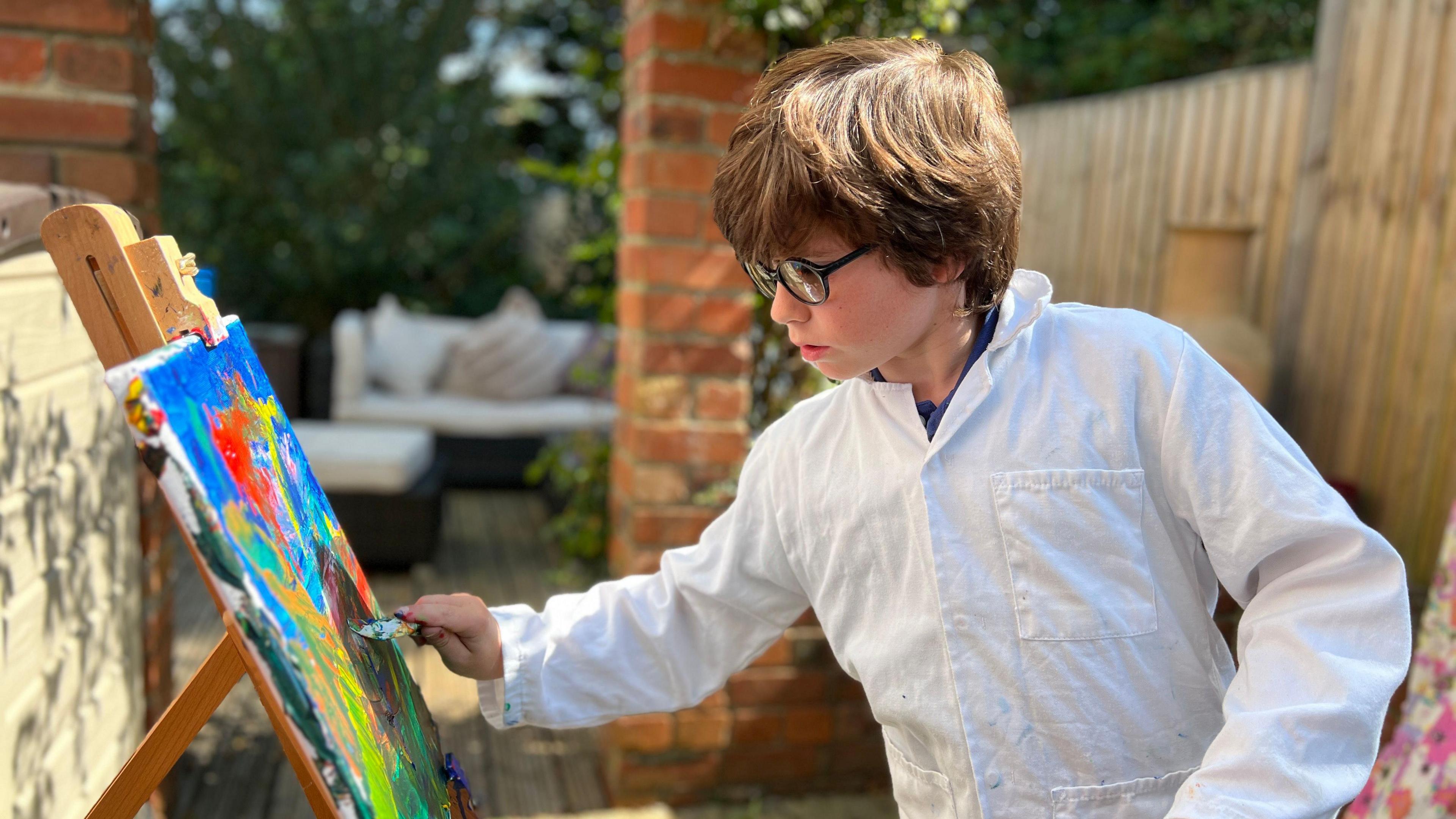 Scott wears painting whites while painting on a canvas