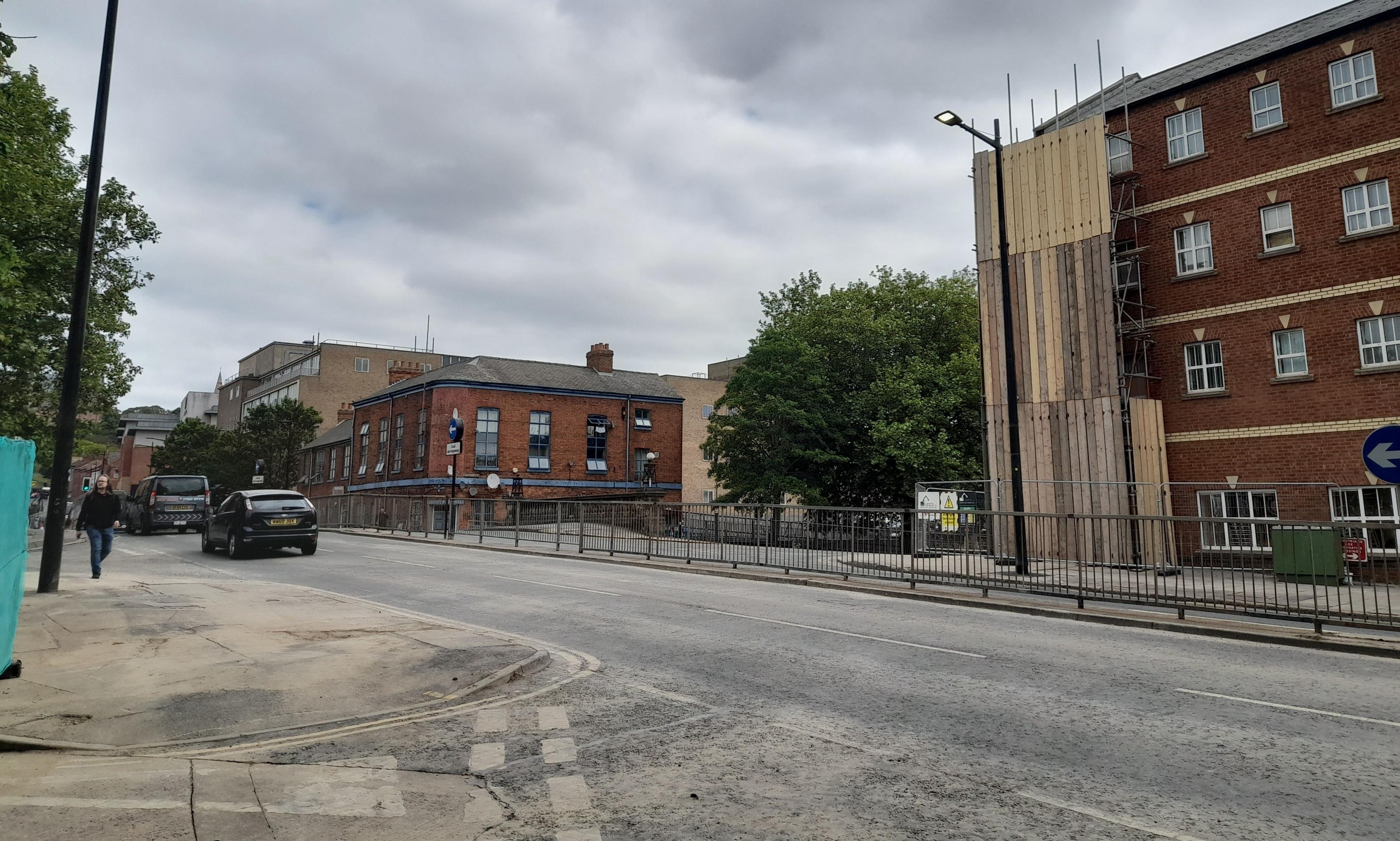 A picture of the area after the demolition. There are a few cars in view and buildings on the right of the road.