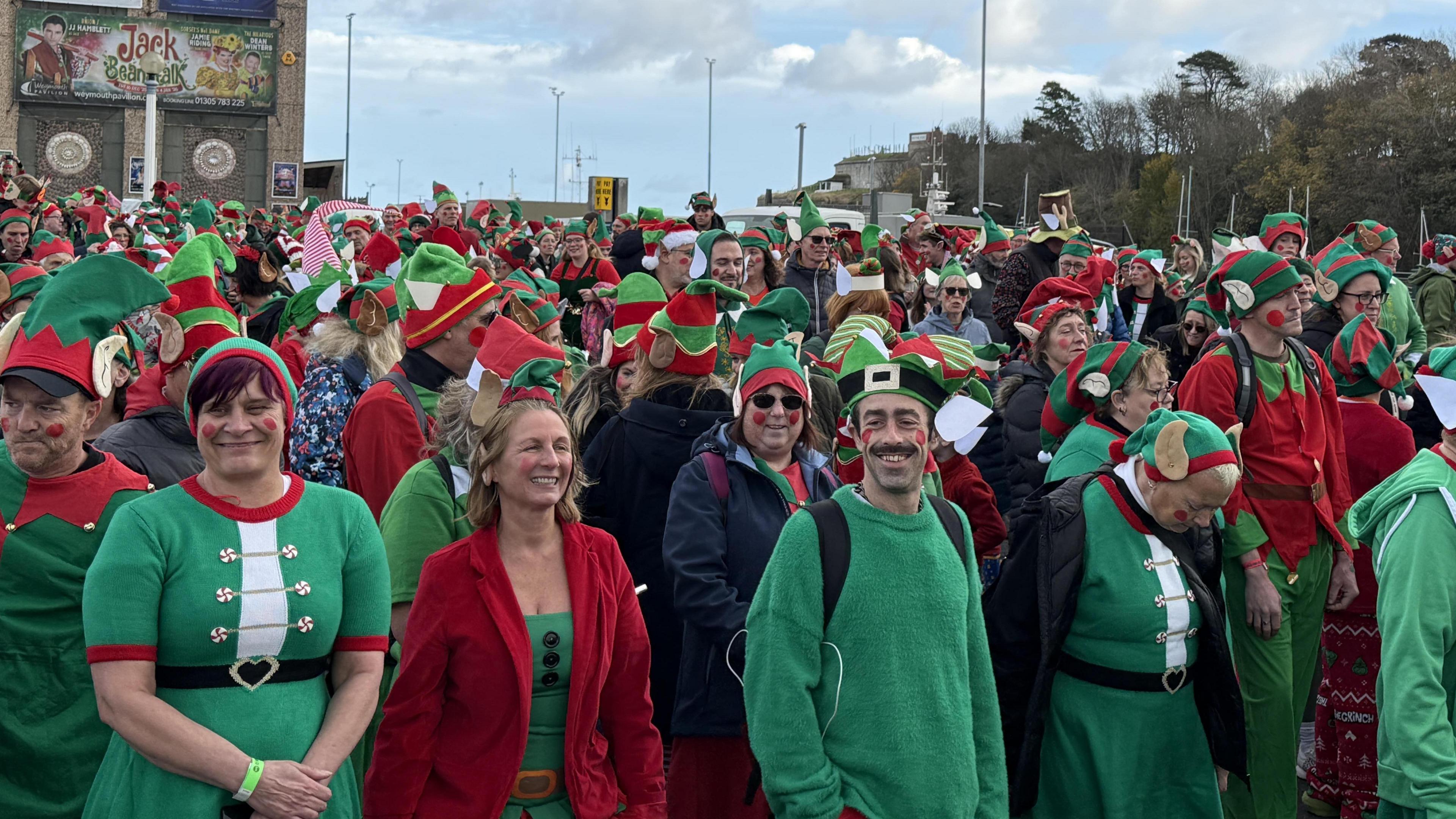 A group of people wearing red, white and green elf costumes.