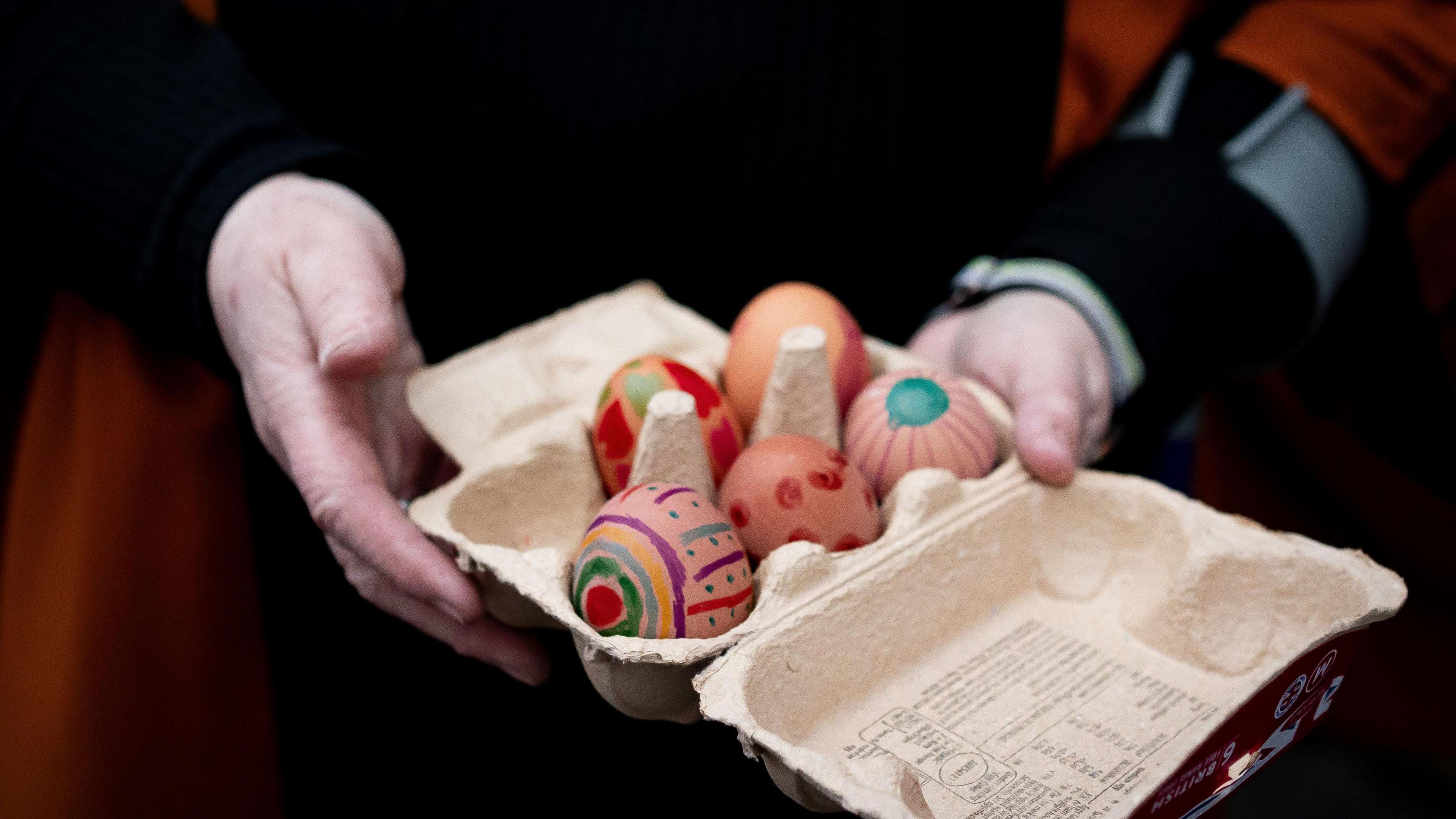 Person displays carton of decorated eggs