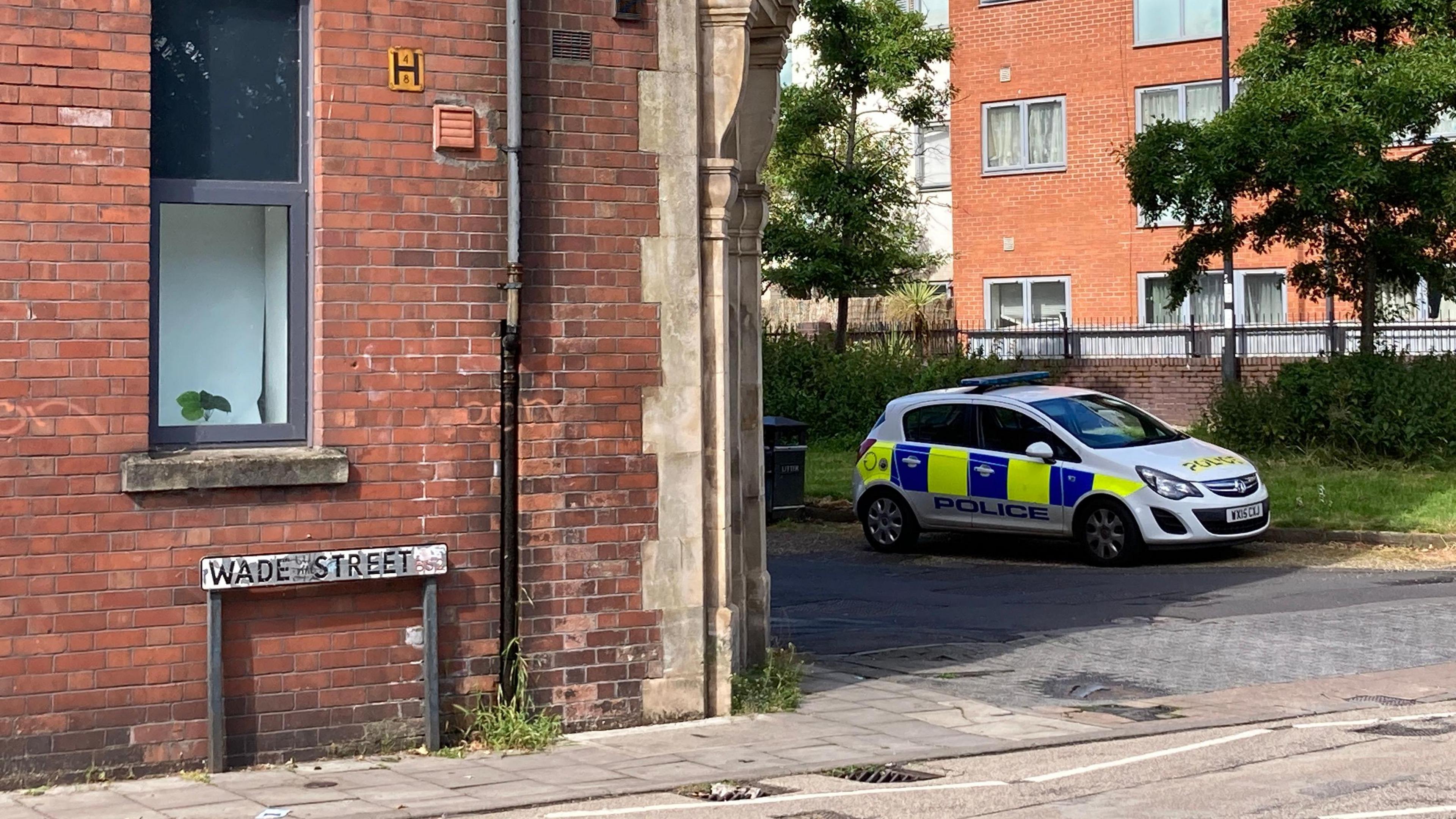 Wade Street street sign, with a Corsa police car around the corner 