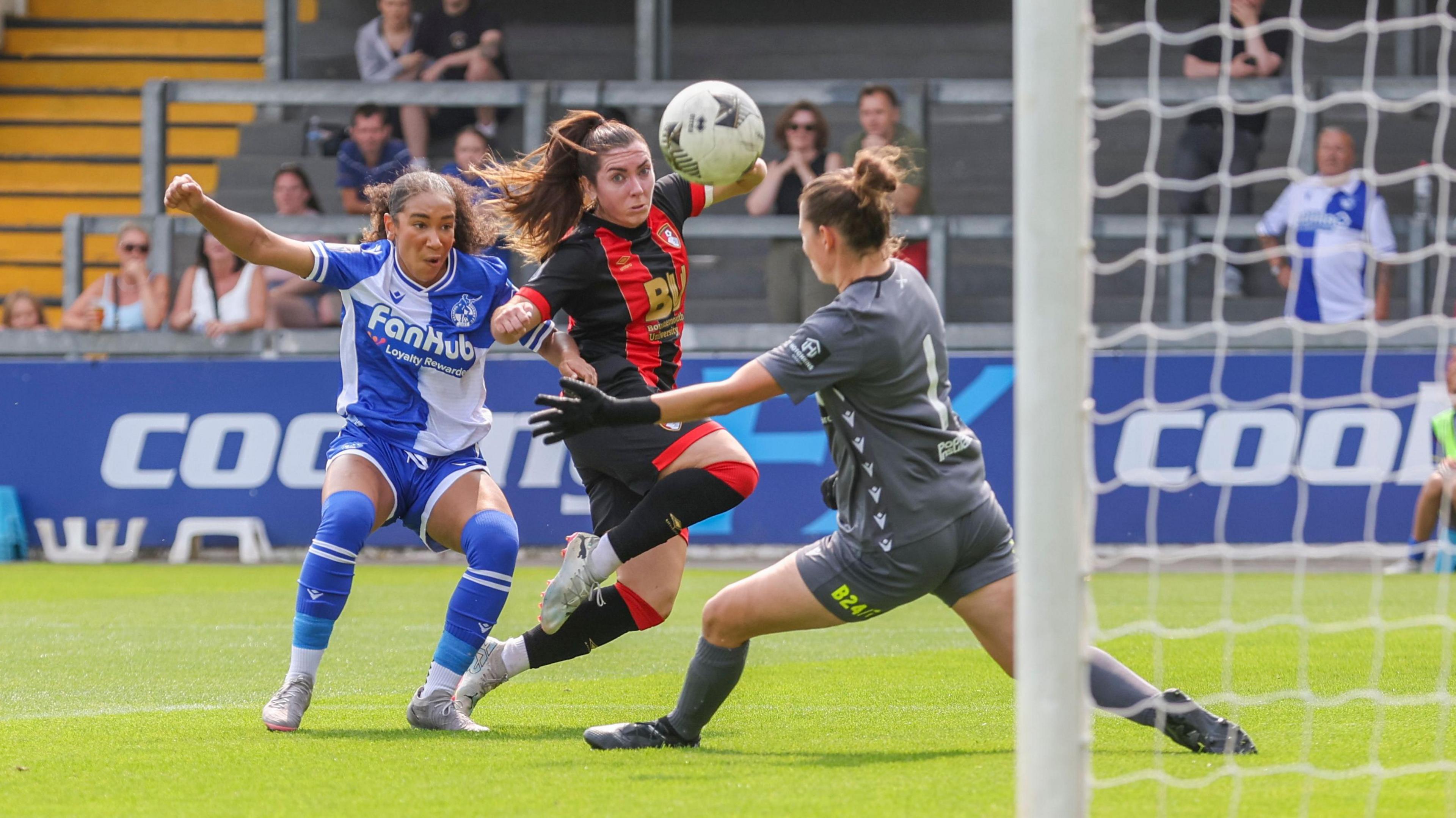 Players from Bristol Rovers Women and AFC Bournemouth Women football teams tussle for the ball at the Memorial Stadium in Bristol. The ball is seen flying past the Rovers goalkeeper on its way into the net