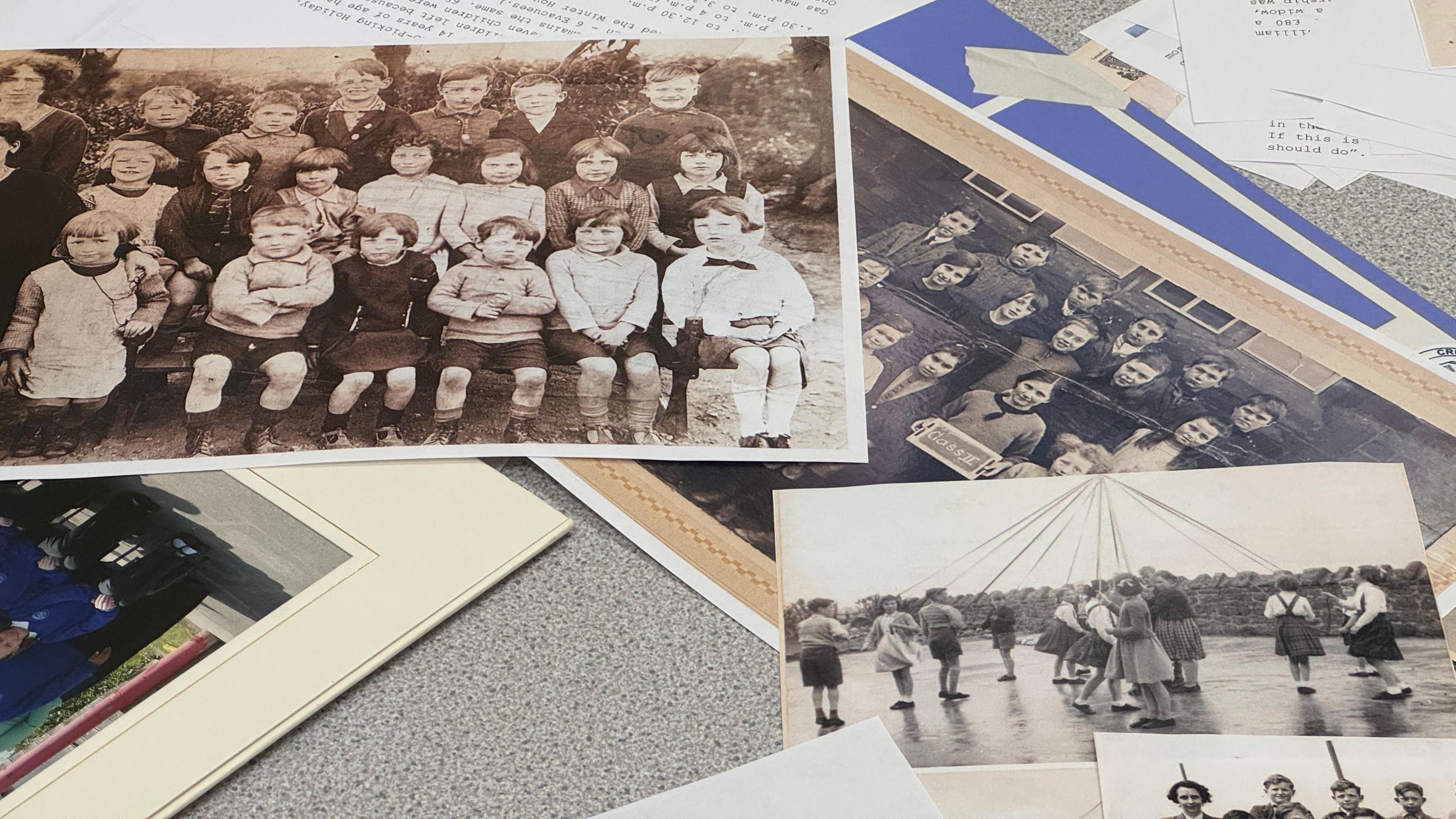 A pile of various old school photographs depicting students from years passed. One shows pupils sitting on three tiers in a class photo. Another shows children around a maypole.