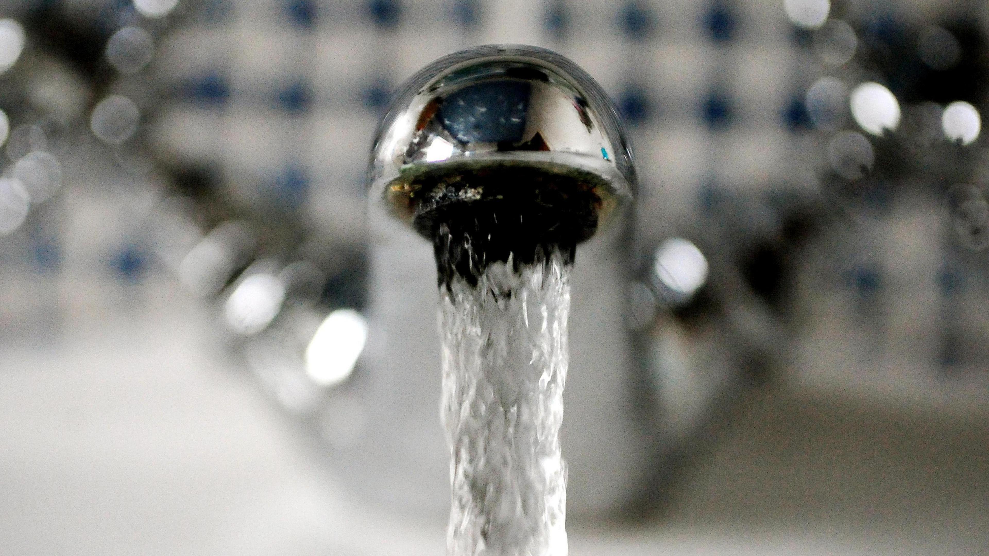 Close up photograph of a shiny, silver-coloured running tap against a blurred background