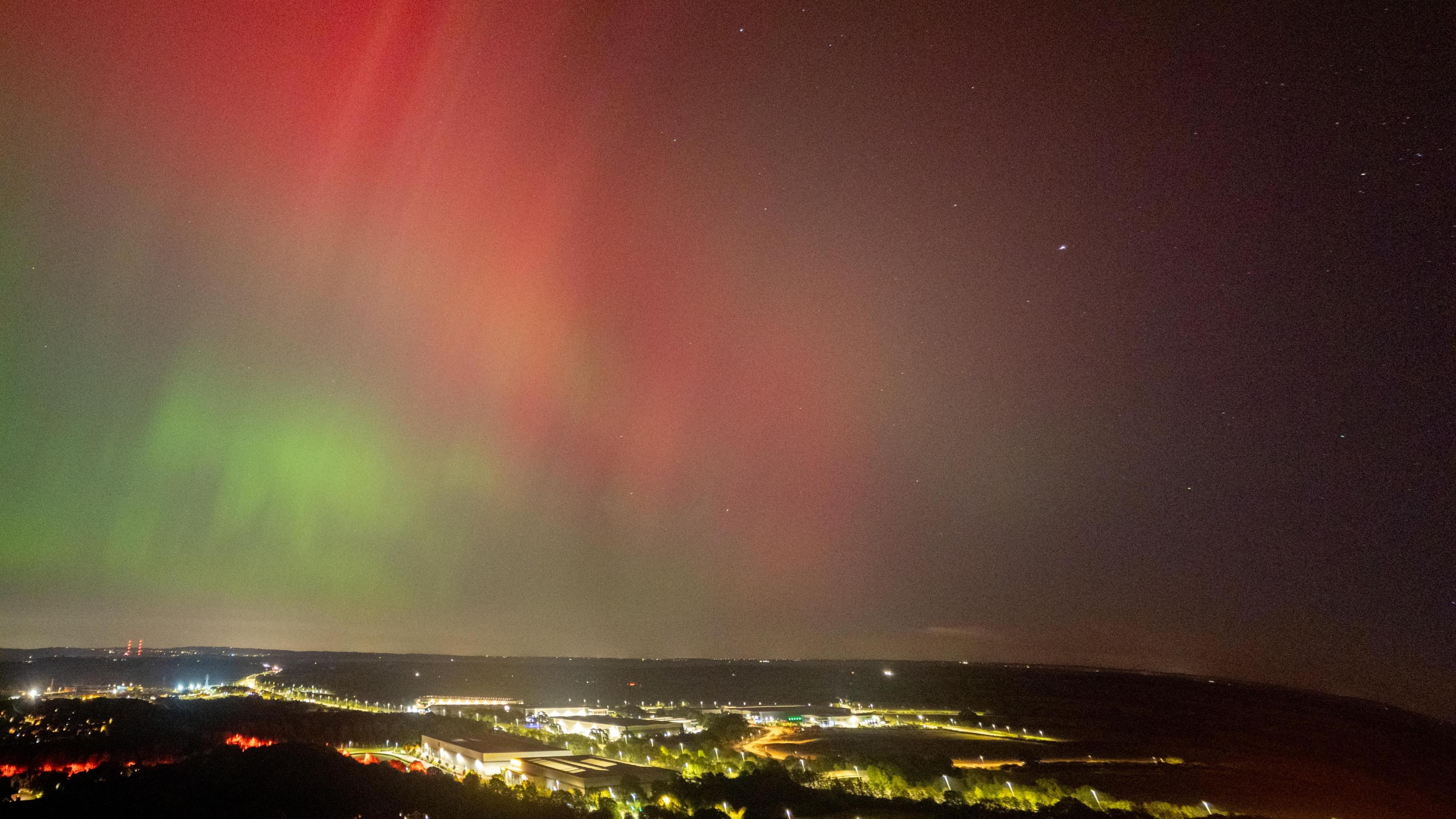 The city centre of Worcester lit up below, with red and yellow colours dancing above it