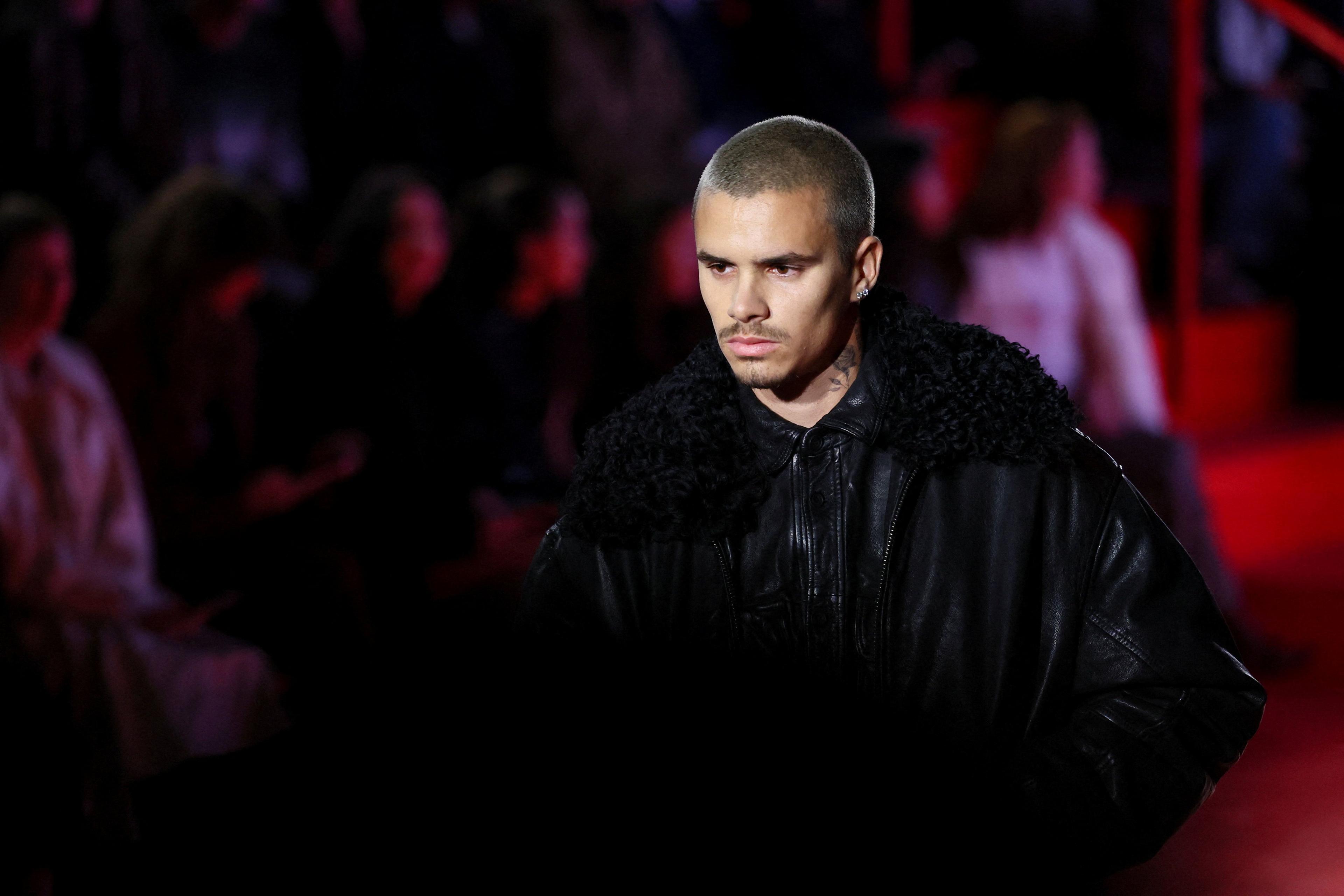 Romeo Beckham wearing a black leather jacket and black cargo pants.