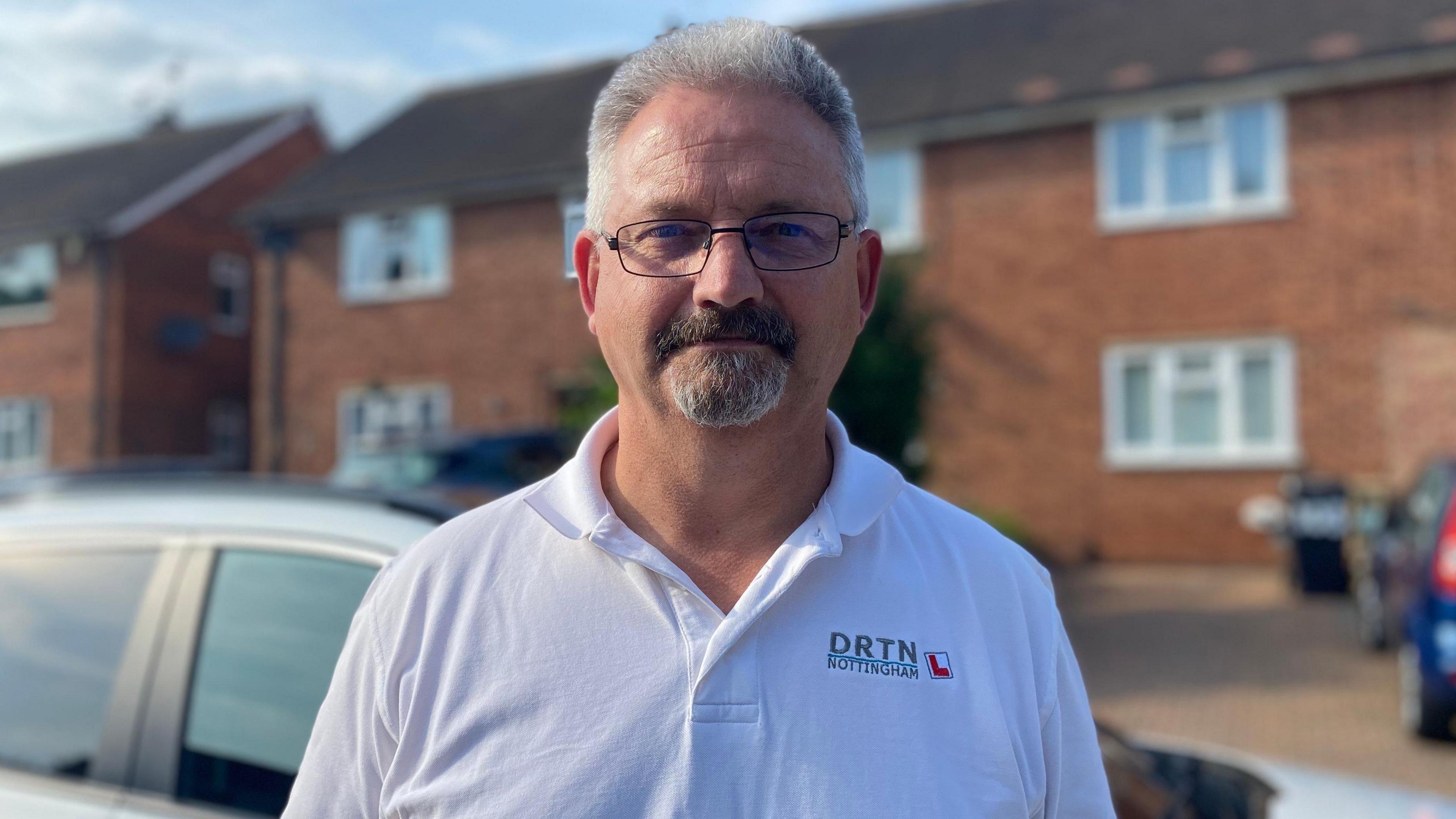 An image of driving instructor Paul Whitburn standing in front of his car